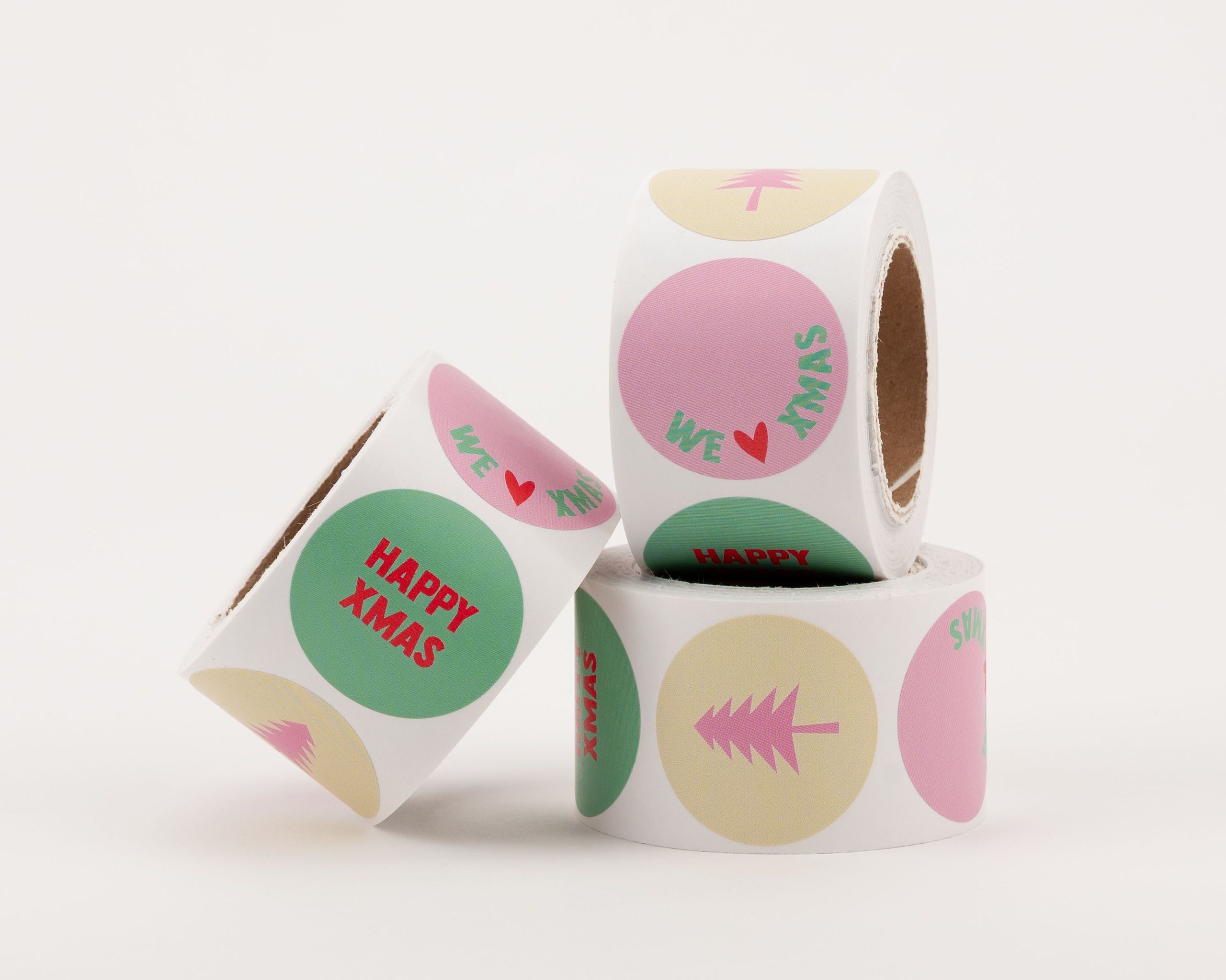 Runde Aufkleber mit verschiedenen Designs in Beige, Pink, Grün. Motive sind 'Happy Xmas', 'We Love Xmas' und ein Weihnachtsbaum