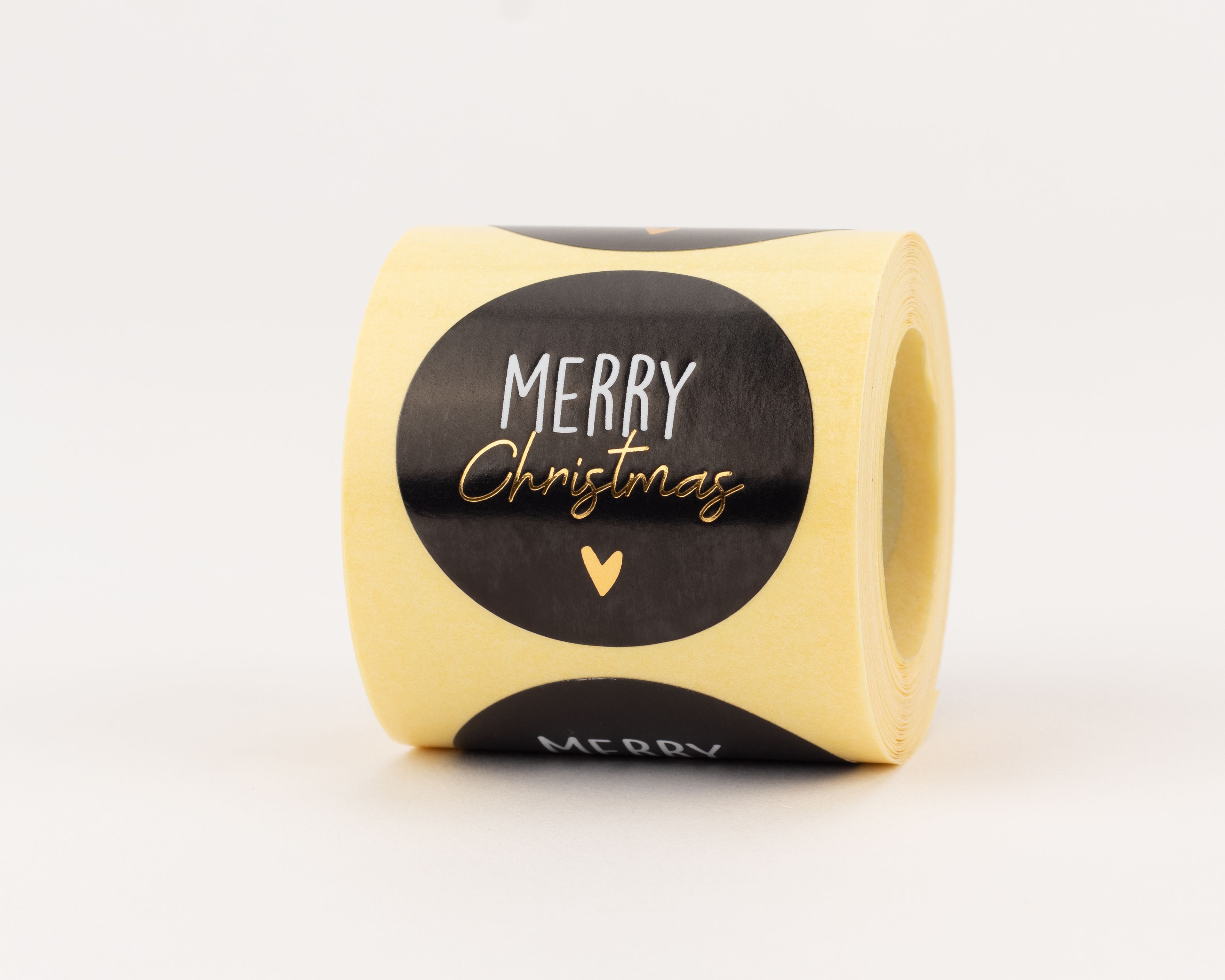 Aufkleber mit schwarzem Hintergrund und weißem "MERRY" Schriftzug. Darunter ist das Wort "Christmas" in Gold-Effekt und ein kleines goldenes Herz zu sehen