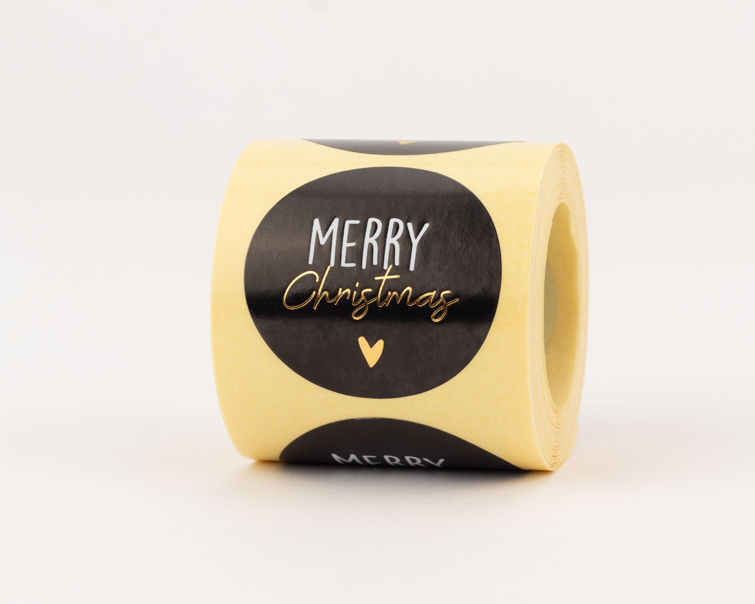Aufkleber mit schwarzem Hintergrund und weißem "MERRY" Schriftzug. Darunter ist das Wort "Christmas" in Gold-Effekt und ein kleines goldenes Herz zu sehen