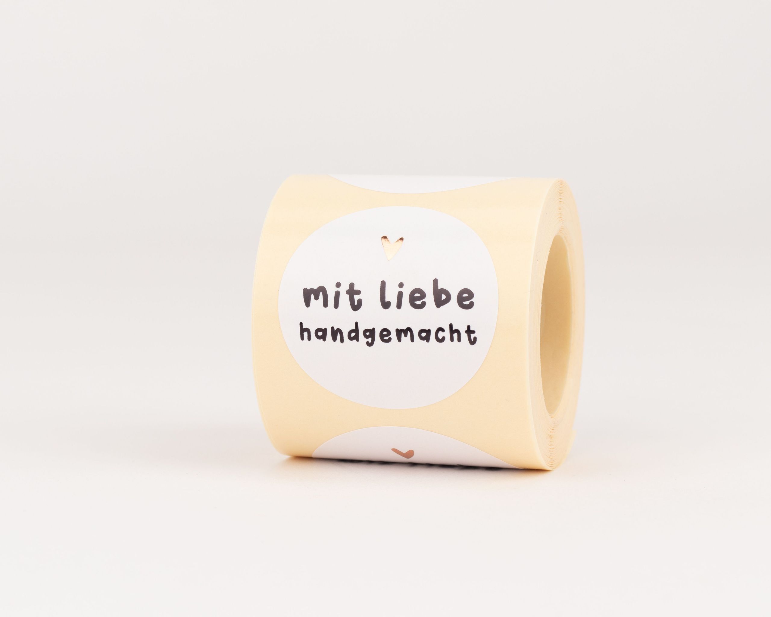 Runde Aufkleber mit weißem Hintergrund, schwarzem Text "mit Liebe handgemacht" und einem roségoldenen Herz