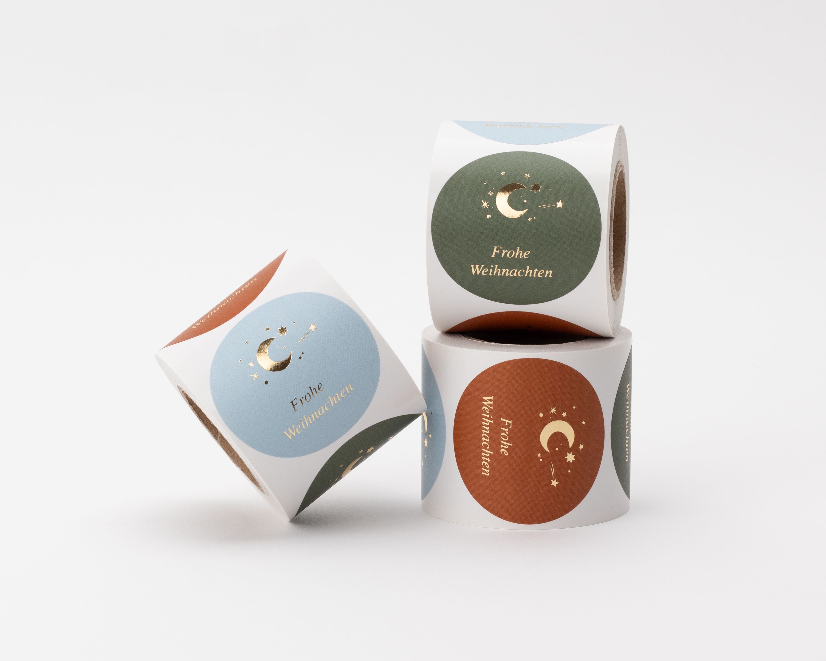 Aufkleber mit drei unterschiedlichen Weihnachtsmotiven: goldene Monde, Sterne und Frohe Weihnachten auf blau, grün und rot