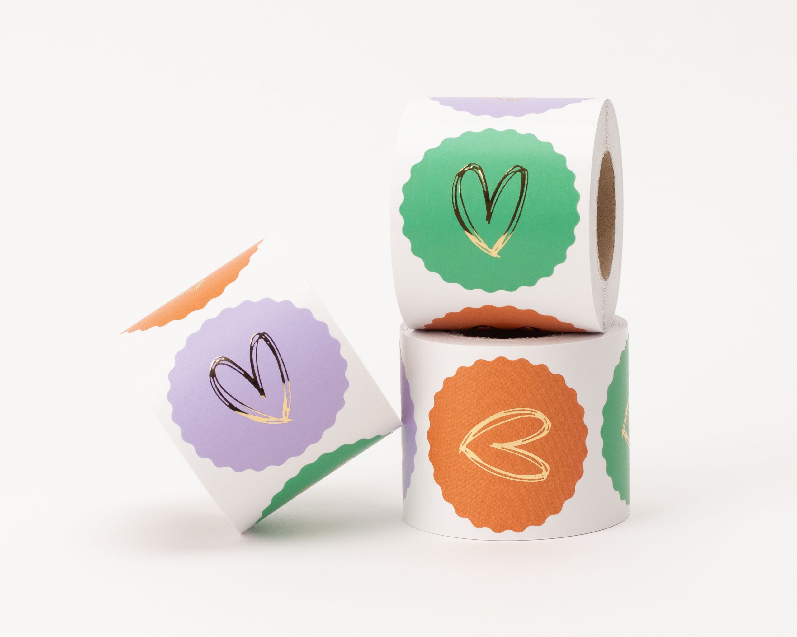 Aufkleber mit drei verschiedenen Designs, jeweils ein goldenes Herz auf farbigem Hintergrund in Flieder Gruen und Orange