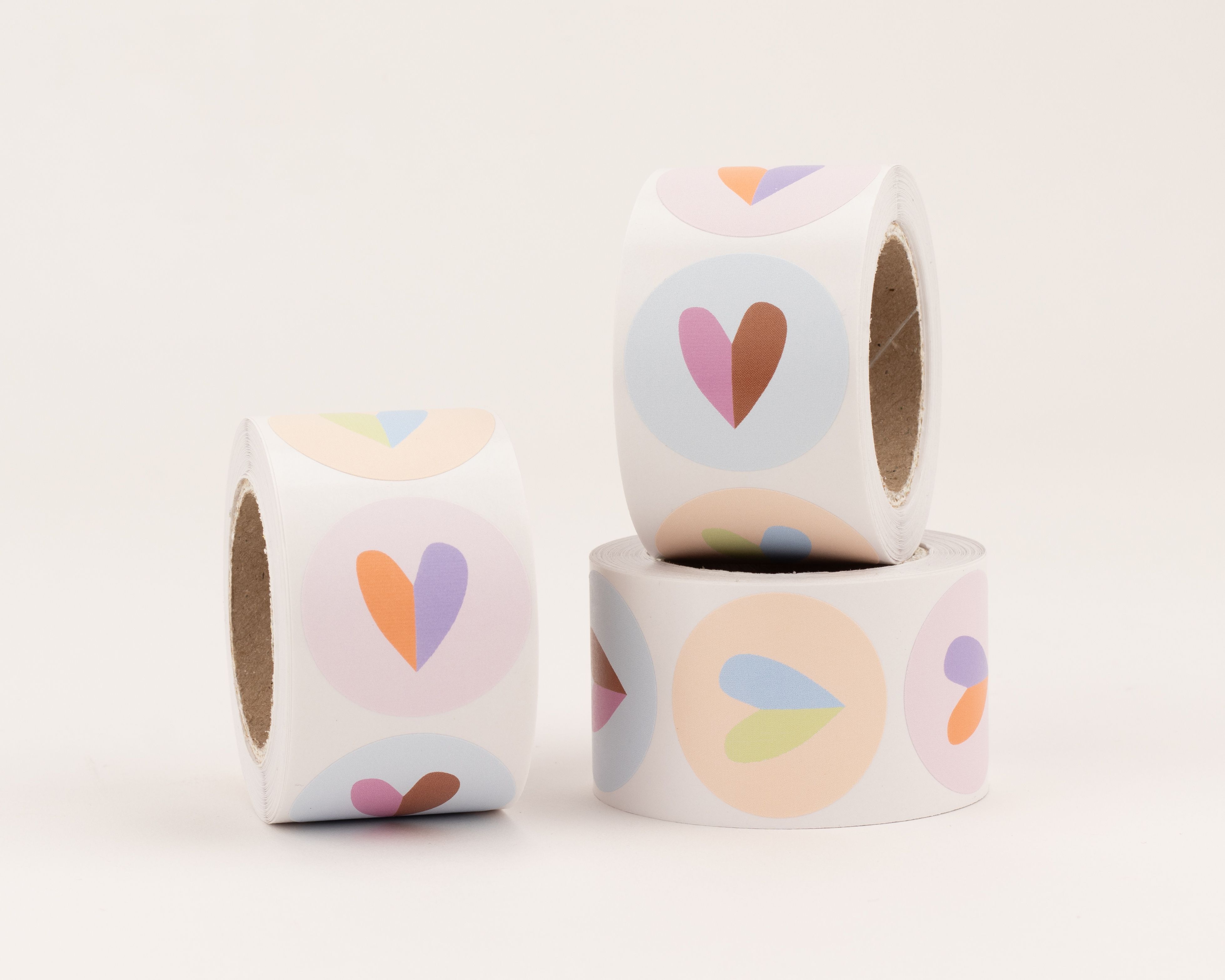 Runde Aufkleber mit drei verschiedenen Herzmotiven in einem Farbmix aus Pastelltönen wie Pink, Braun, Orange und Hellblau