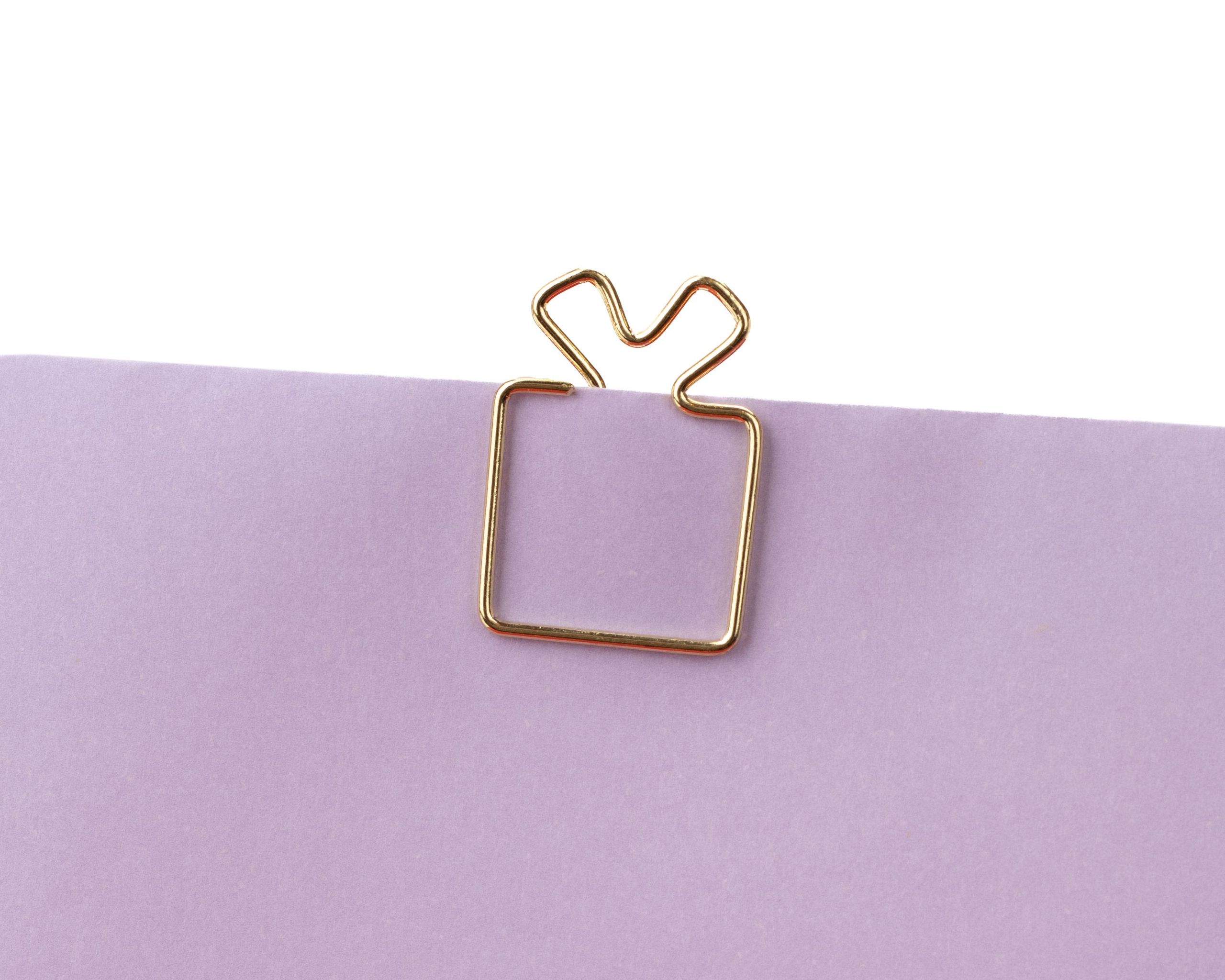Goldfarbene Clips aus Metall, die wie ein kleines Geschenk mit einer Schleife oben geformt sind