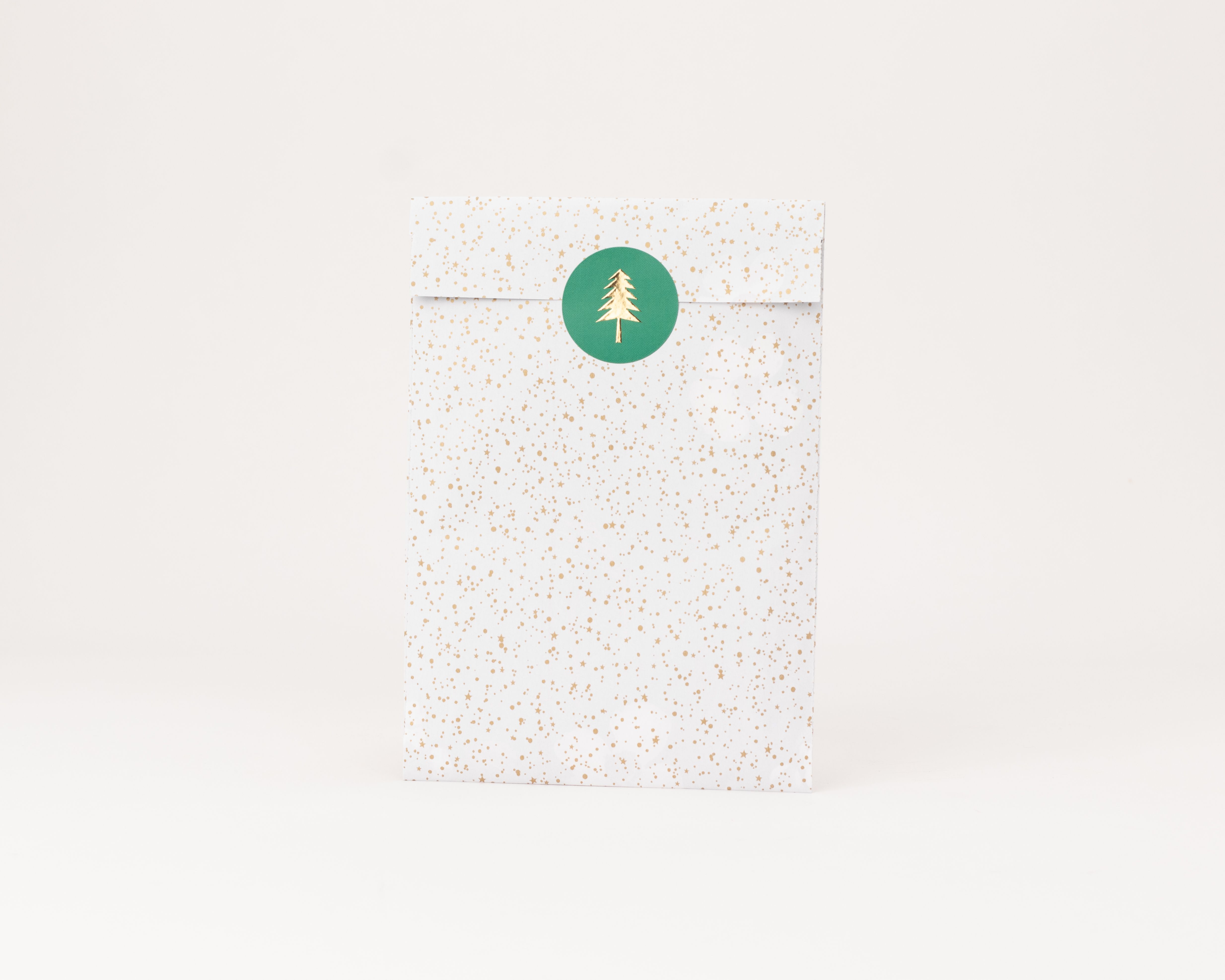 Flachbeutel, weiß mit goldenen Sternen und Punkten, verschlossen durch grünen Weihnachtsbaum-Sticker, Innenseite weiß