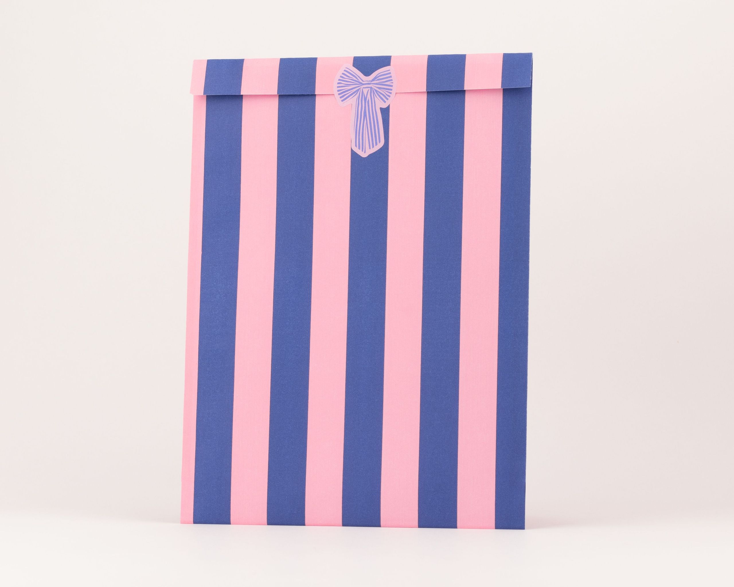 Flachbeutel mit vertikalen Streifen in Blau und Pink, verziert mit einer kleinen Schleife und weißer Innenseite