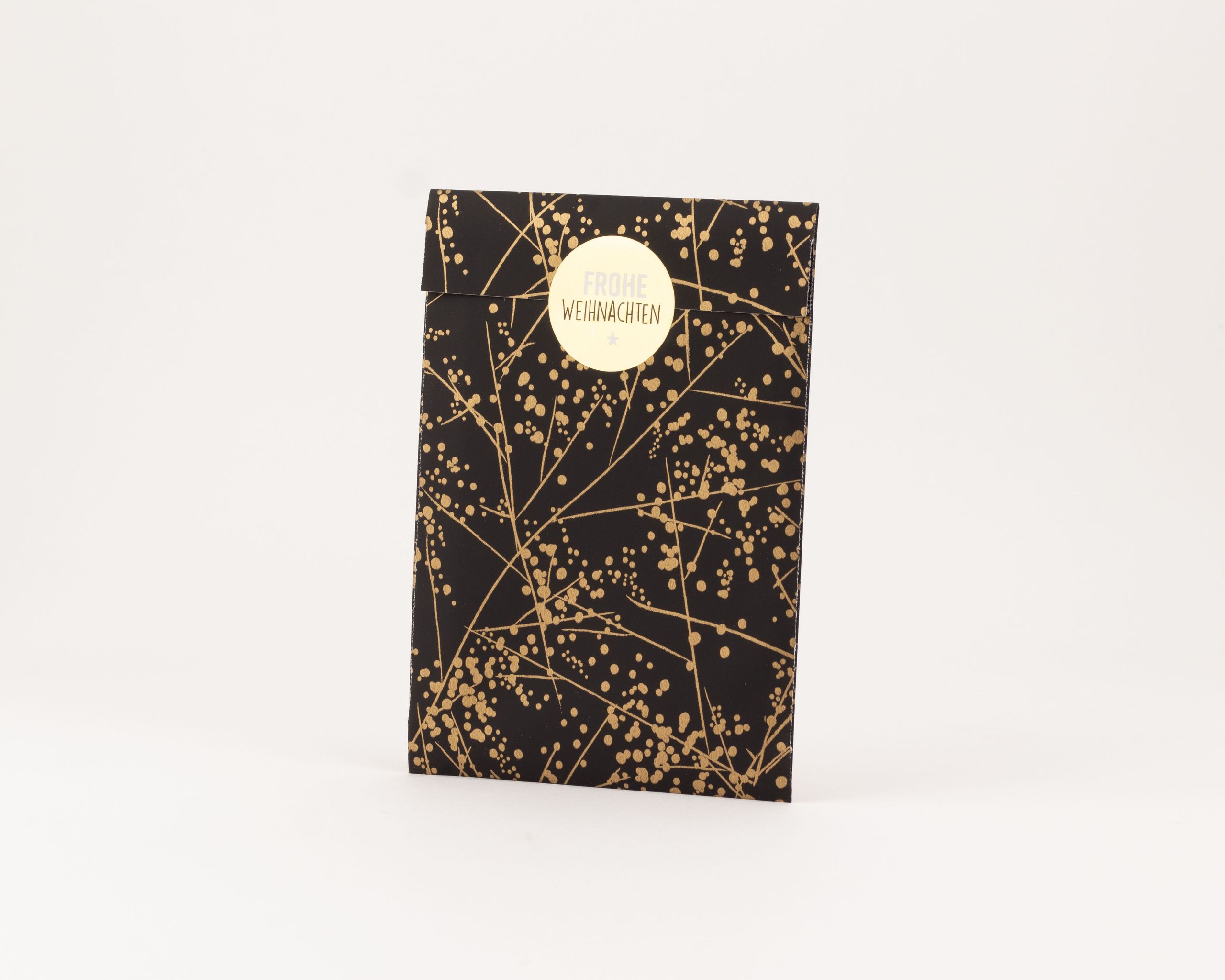 Flachbeutel in Schwarz mit goldenem Winterfrost-Muster und einem runden goldenen 'Frohe Weihnachten' Sticker