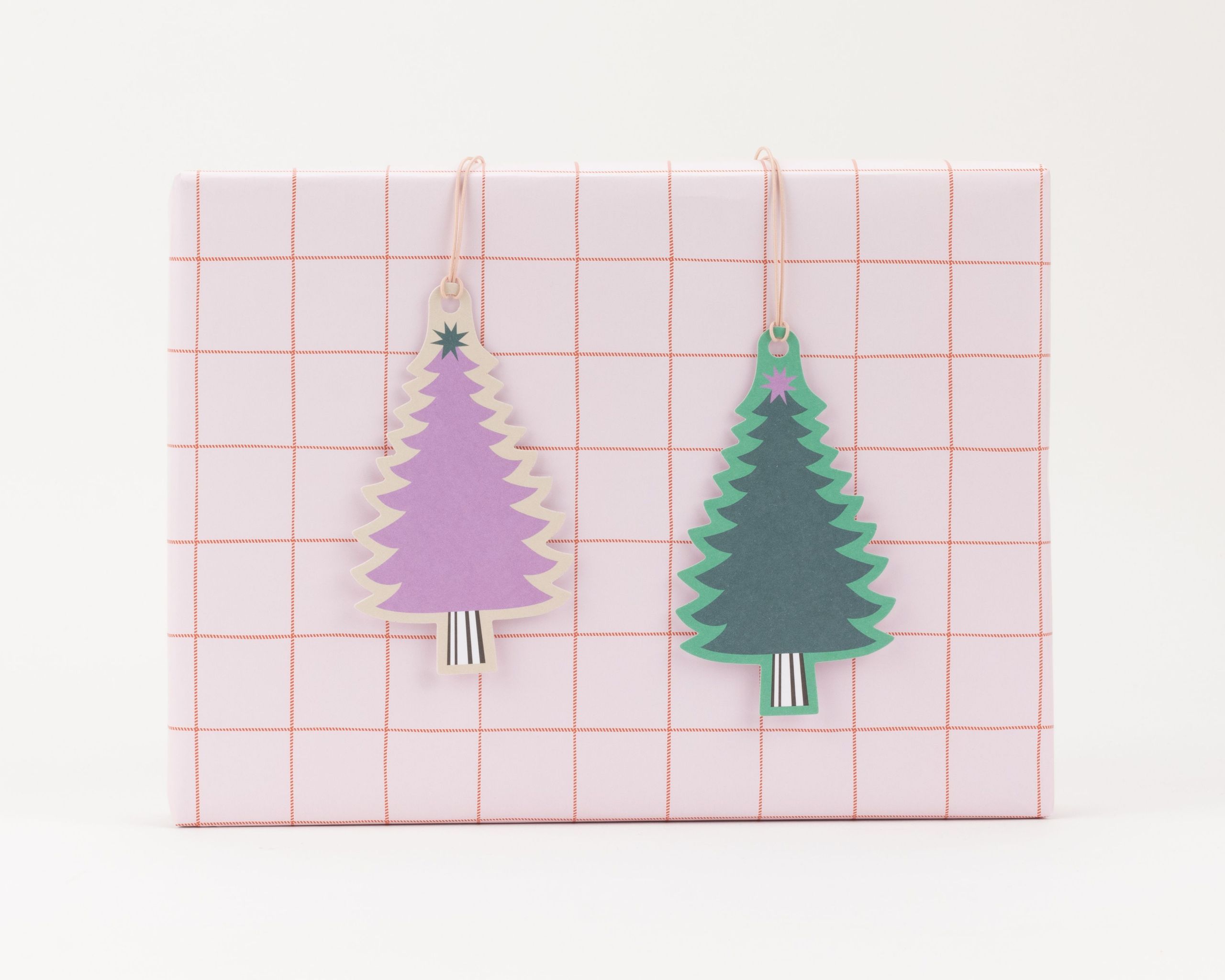 Geschenkanhänger-Set mit zwei nebeneinander hängenden Weihnachtsbaum-Anhängern in Lila und Dunkelgrün mit hellem Rand