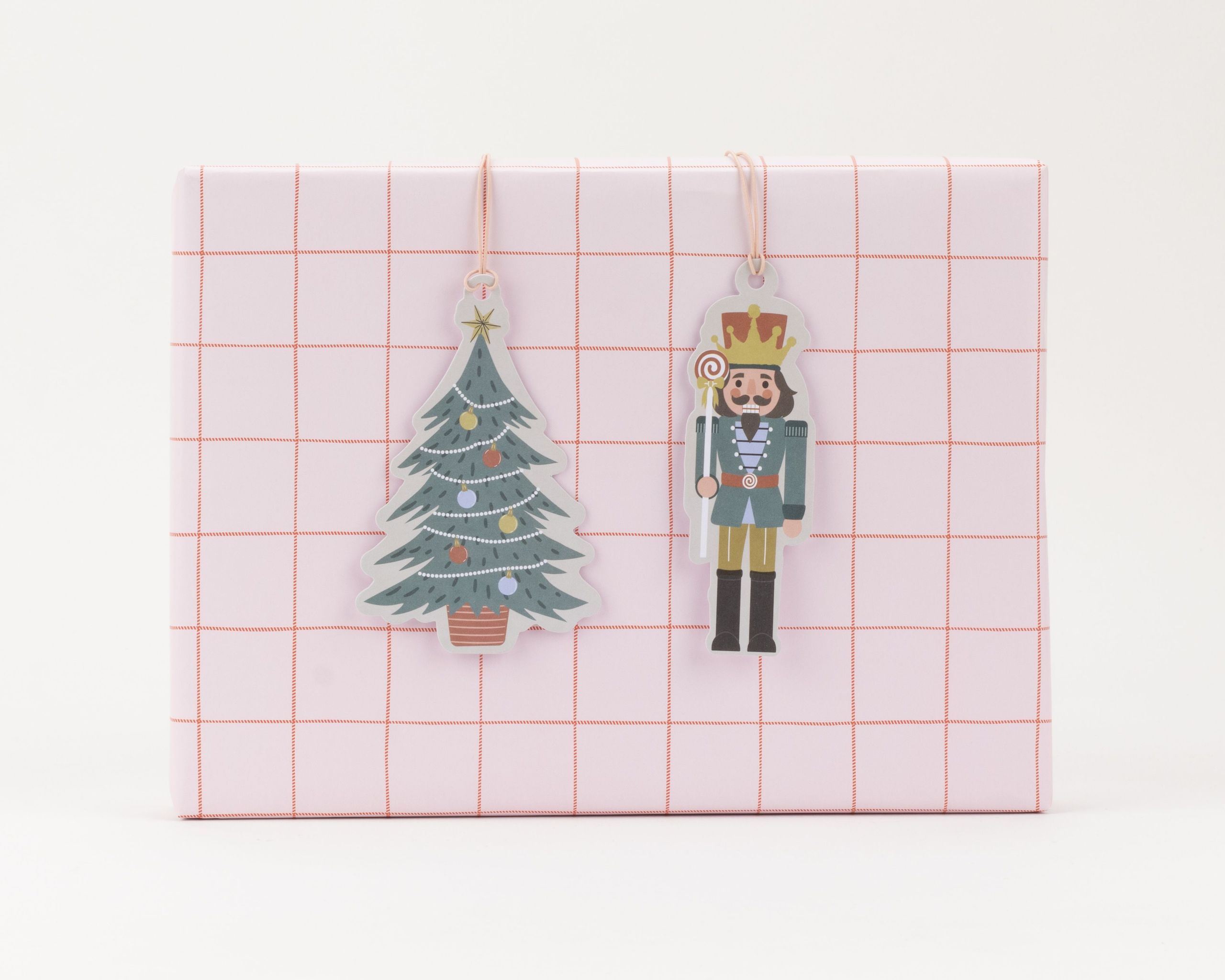 Geschenkanhänger-Set mit zwei nebeneinander hängenden, weihnachtlichen Anhängern: Ein grüner Weihnachtsbaum und ein Nussknacker in Uniform