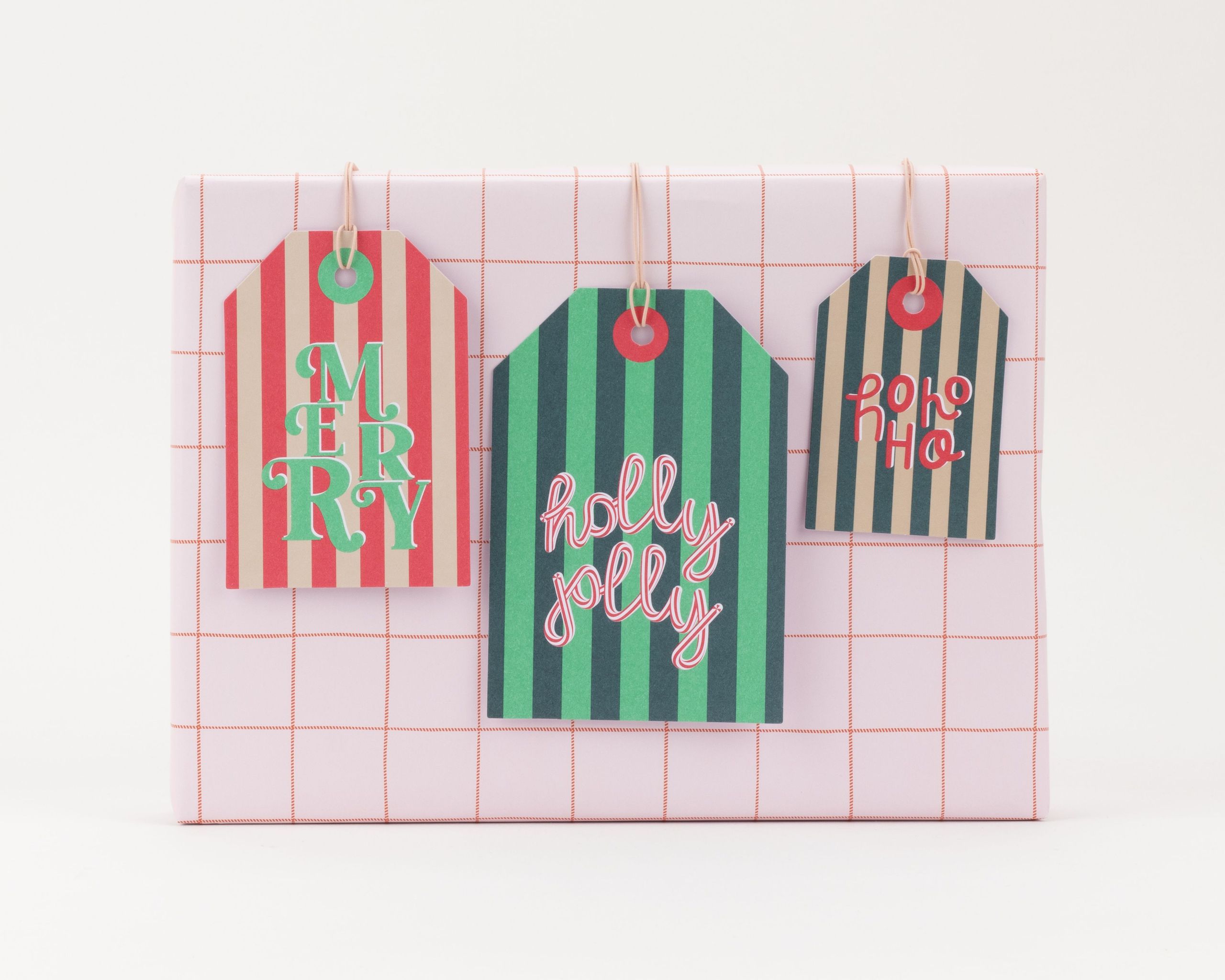 Drei rechteckige Geschenkanhänger, gestreift in Rot, Grün, Beige. Sie zeigen die Schriftzüge Merry, Holly Jolly und ho ho ho