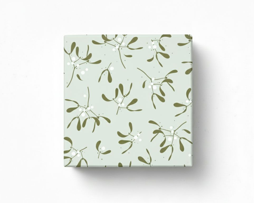 Geschenkpapier mit einem Mistelzweig-Muster in Olivgrün und weißen Beeren auf salbeigrünem Grund, präsentiert als verpacktes Geschenk