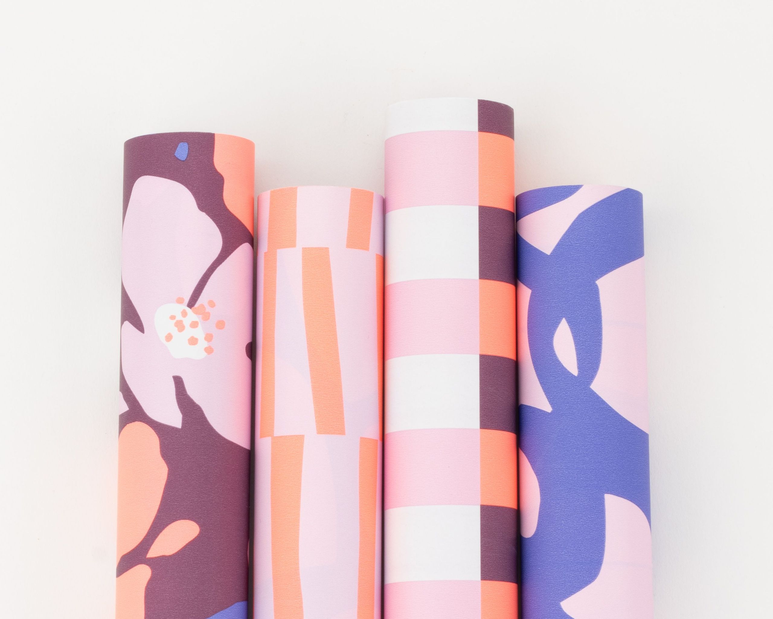 Geschenkpapier-Set mit vier Rollen in lebhaften Farbtönen wie Plum, Orange, Flieder und Blau mit floralen und grafischen Mustern