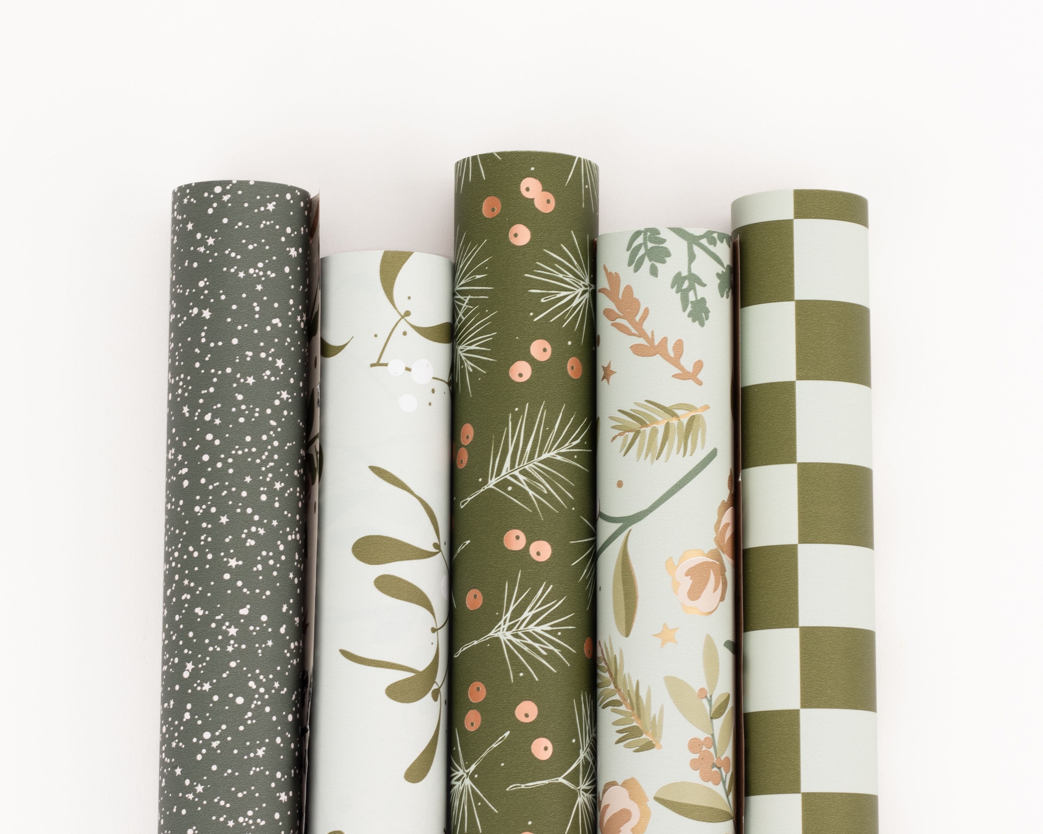 Geschenkpapier-Set mit fünf Rollen in Grüntönen. Die Rollen zeigen diverse Muster wie Sterne, botanische Blätter, Beeren, Blumen und Streifen
