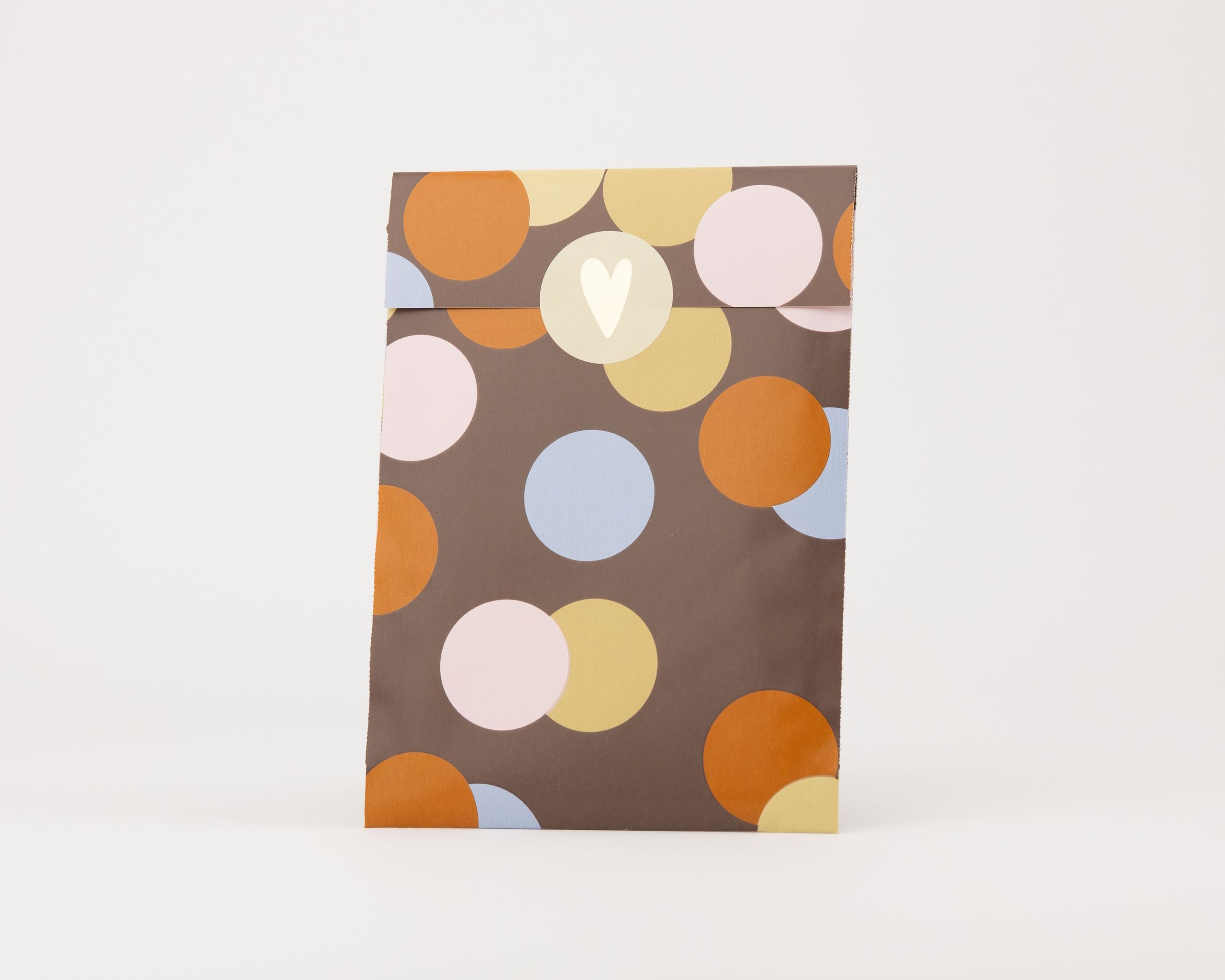 Papiertüten Flachbeutel mit braunem Hintergrund und einem Konfettimuster aus Kreisen in Gold, Hellblau, Orange und Beige, verziert mit einem hellen Herzmotiv
