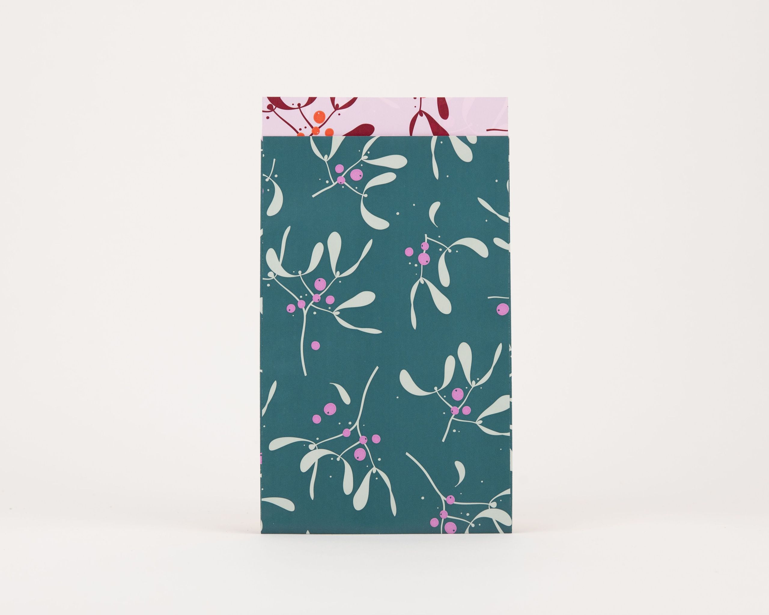 Papiertüten Flachbeutel mit einem Mistelzweig-Muster in Petrol, Hellgrün und Magenta auf der Außenseite, und einer Innenseite in Rosa mit weinrotem Muster