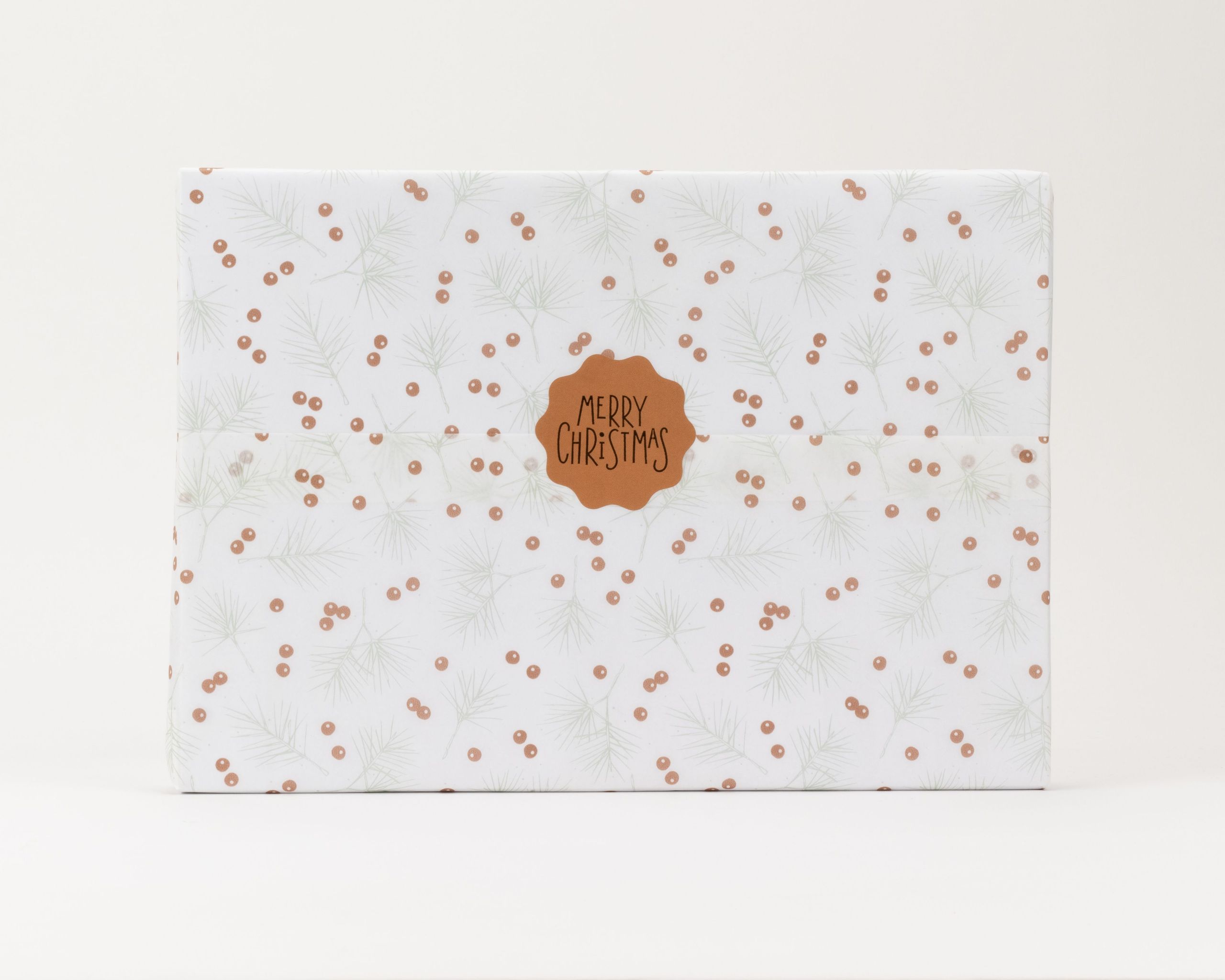 Seidenpapier mit einem Muster aus hellgrünen Tannenzweigen und kleinen ockerfarbenen Beeren auf weißem Hintergrund