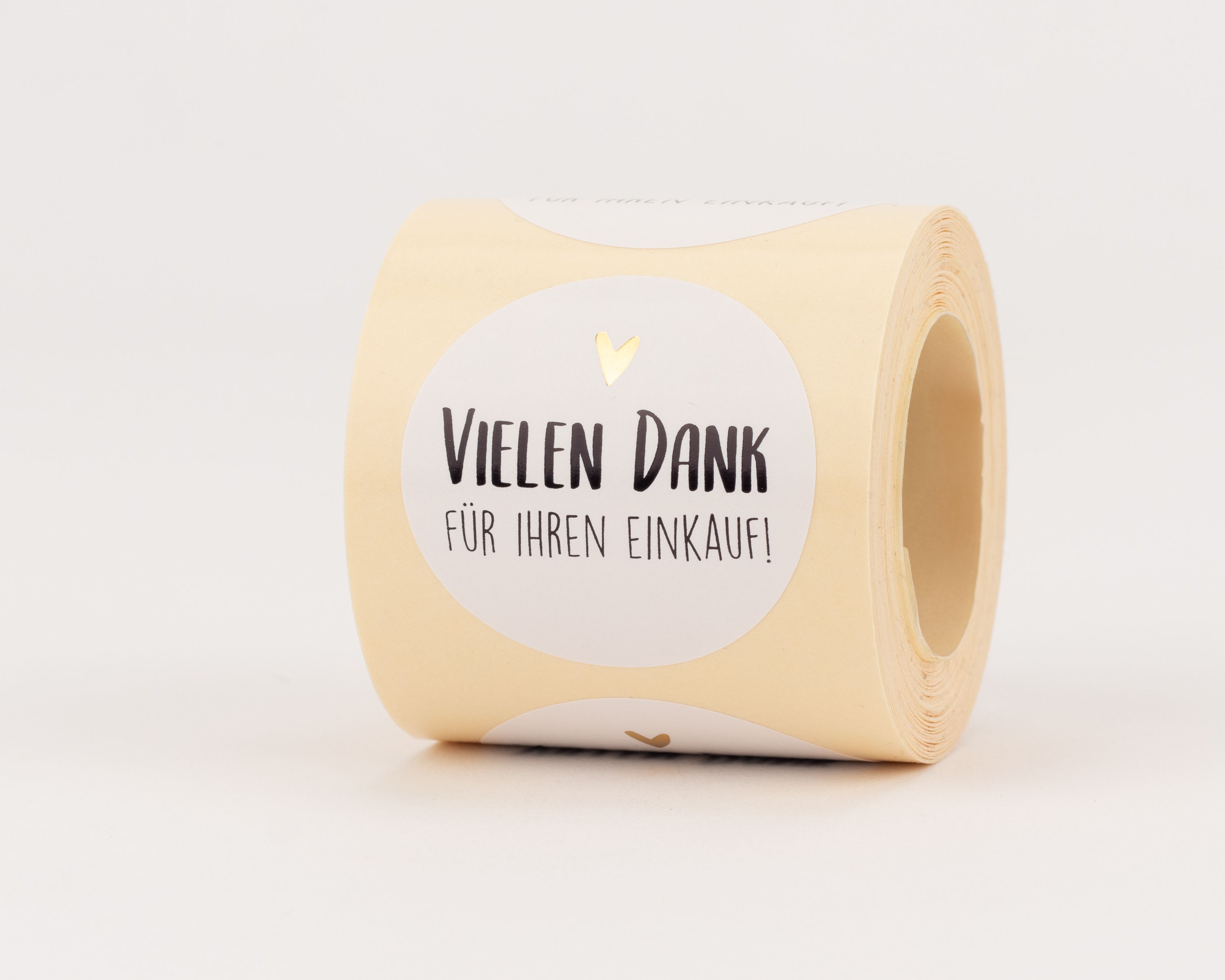 Aufkleber mit beigem Grund und weißem Rundetikett. Darauf der schwarze Text 'VIELEN DANK FÜR IHREN EINKAUF!' und ein kleines goldenes Herz