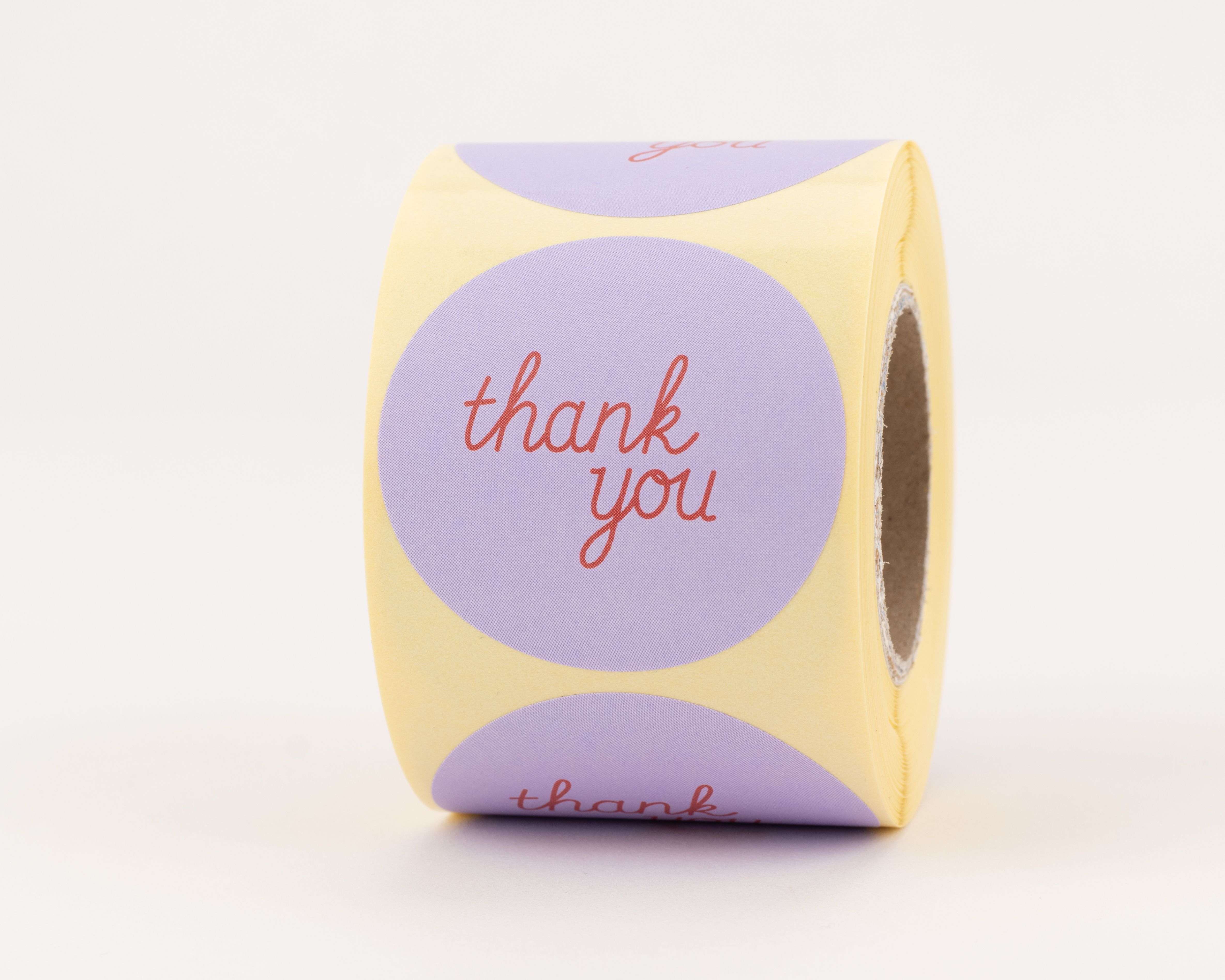 Aufkleber mit rotem thank you Schriftzug auf rundem fliederfarbenem Hintergrund, sichtbar als viele gleichartige Sticker