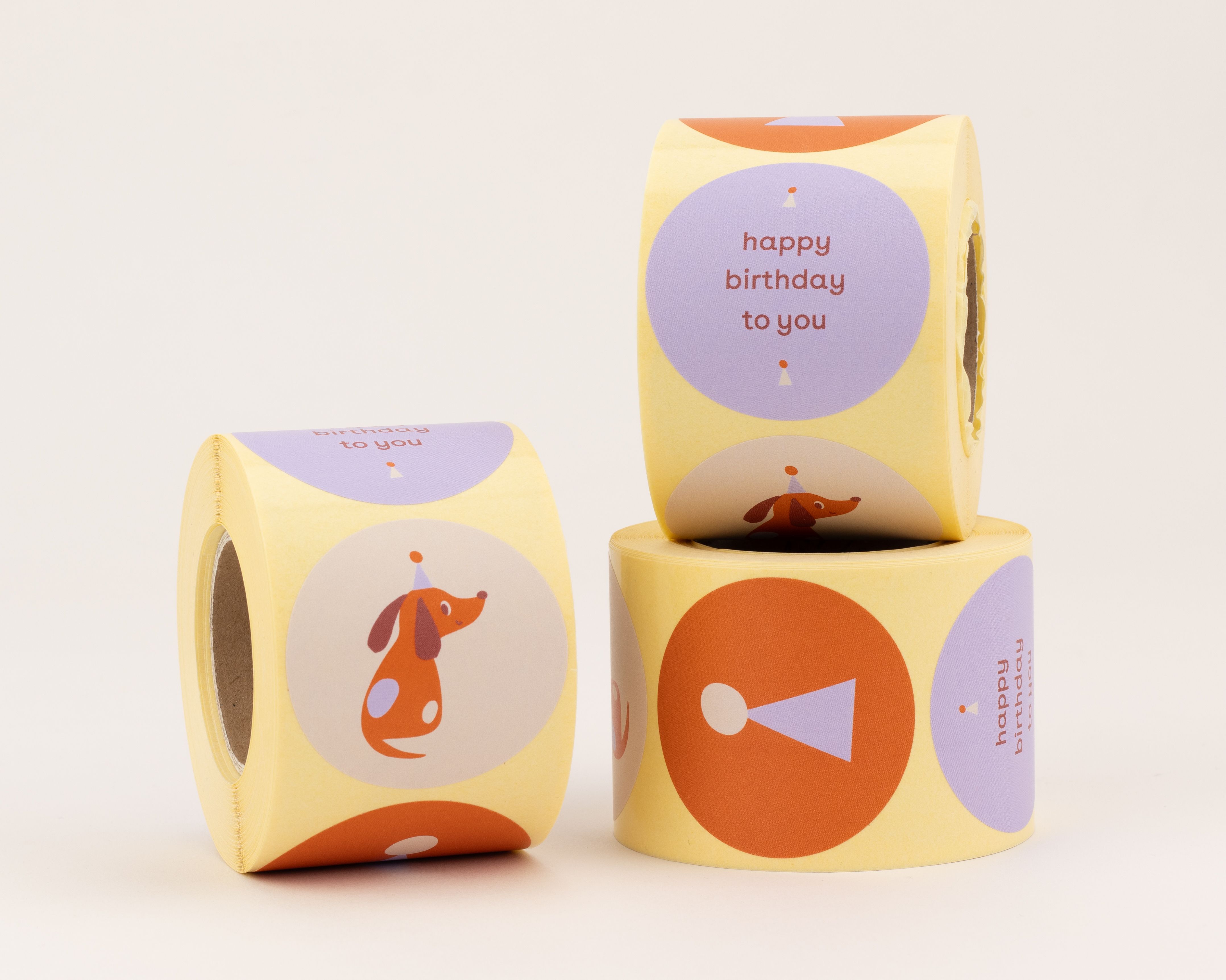 Sticker mit drei runden Designs: Ein Dackel mit Partyhut, 'Happy Birthday' Schriftzug in Lila und ein abstraktes Party-Symbol auf gelbem Grund