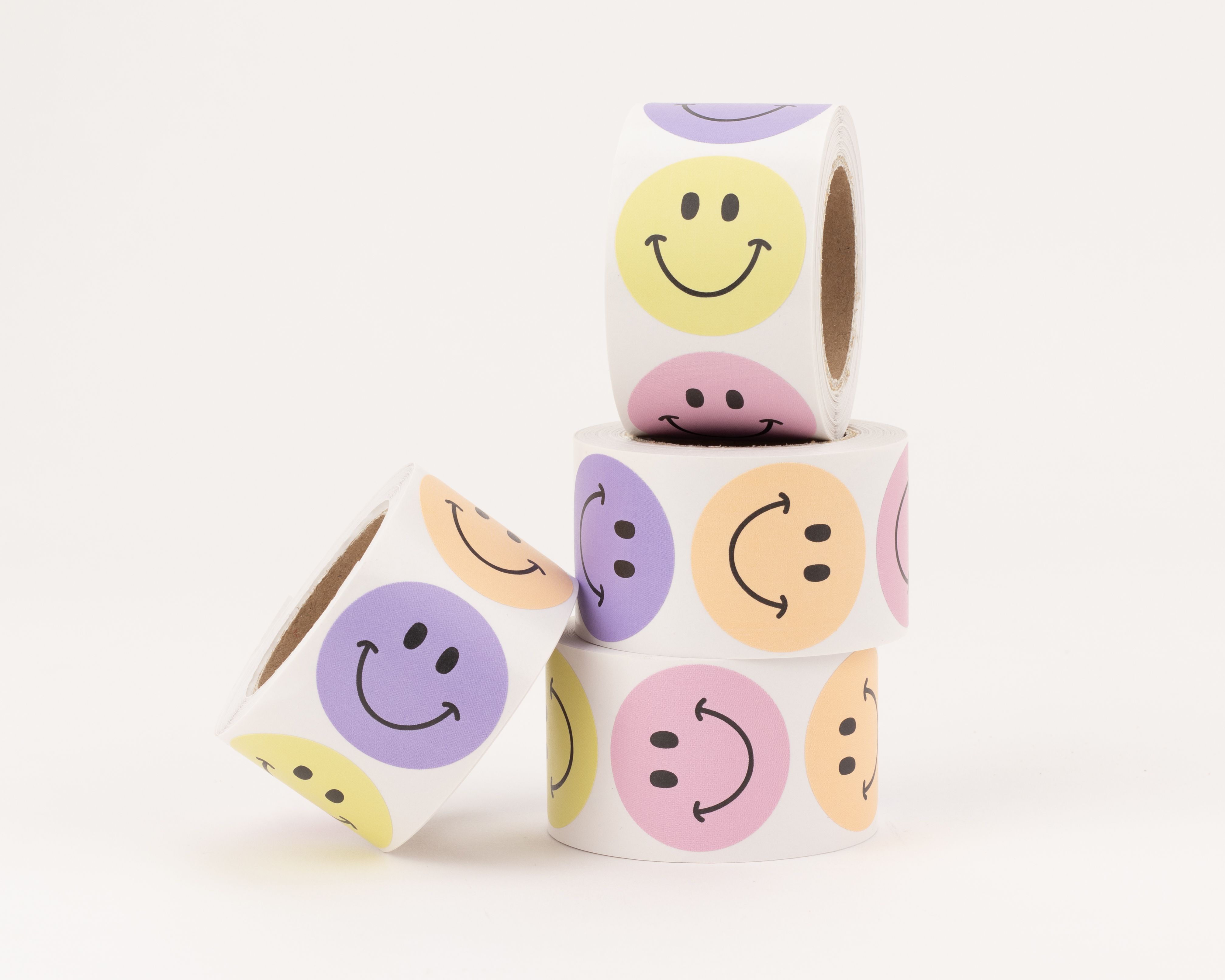 Aufkleber mit vier verschiedenen Smiley-Designs in den Farben Flieder, Gelb, Pfirsich und Rosa