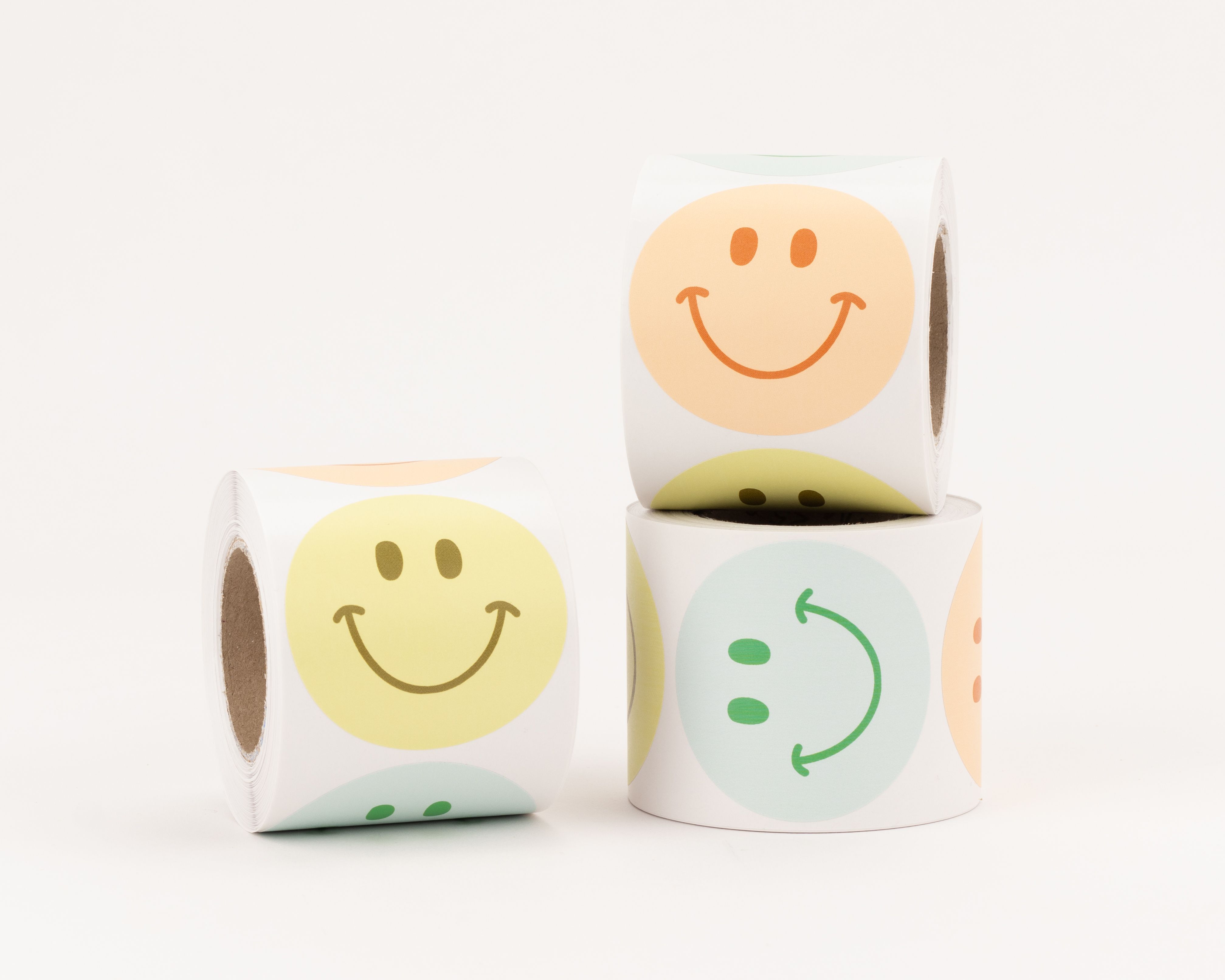 Aufkleber mit drei verschiedenen Smiley-Designs in den Farben Gelb, Pfirsich und Minze, nebeneinander präsentiert