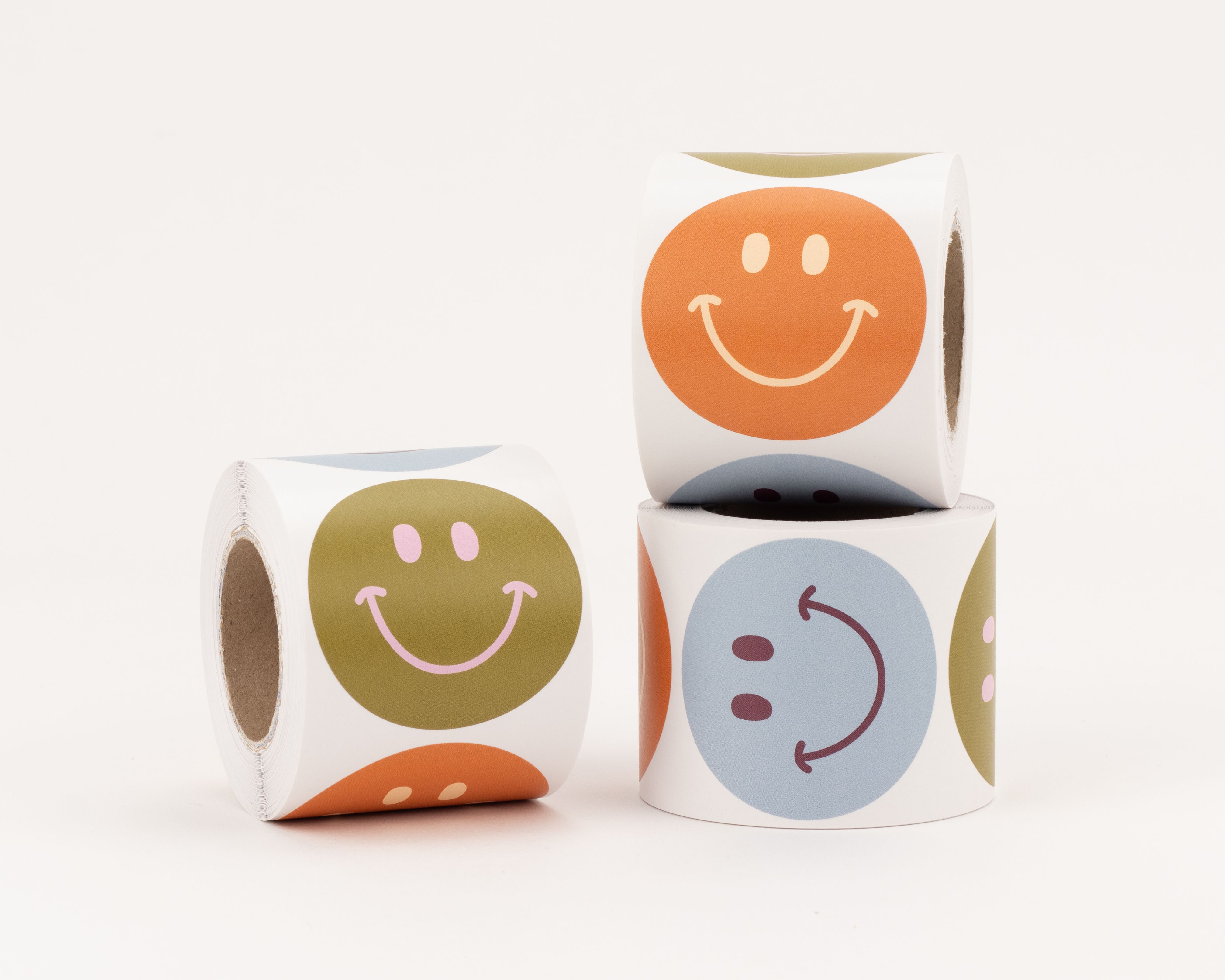Aufkleber in verschiedenen Designs mit lachenden Smiley Gesichtern in den Farben Olivgrün, Rost und Blau