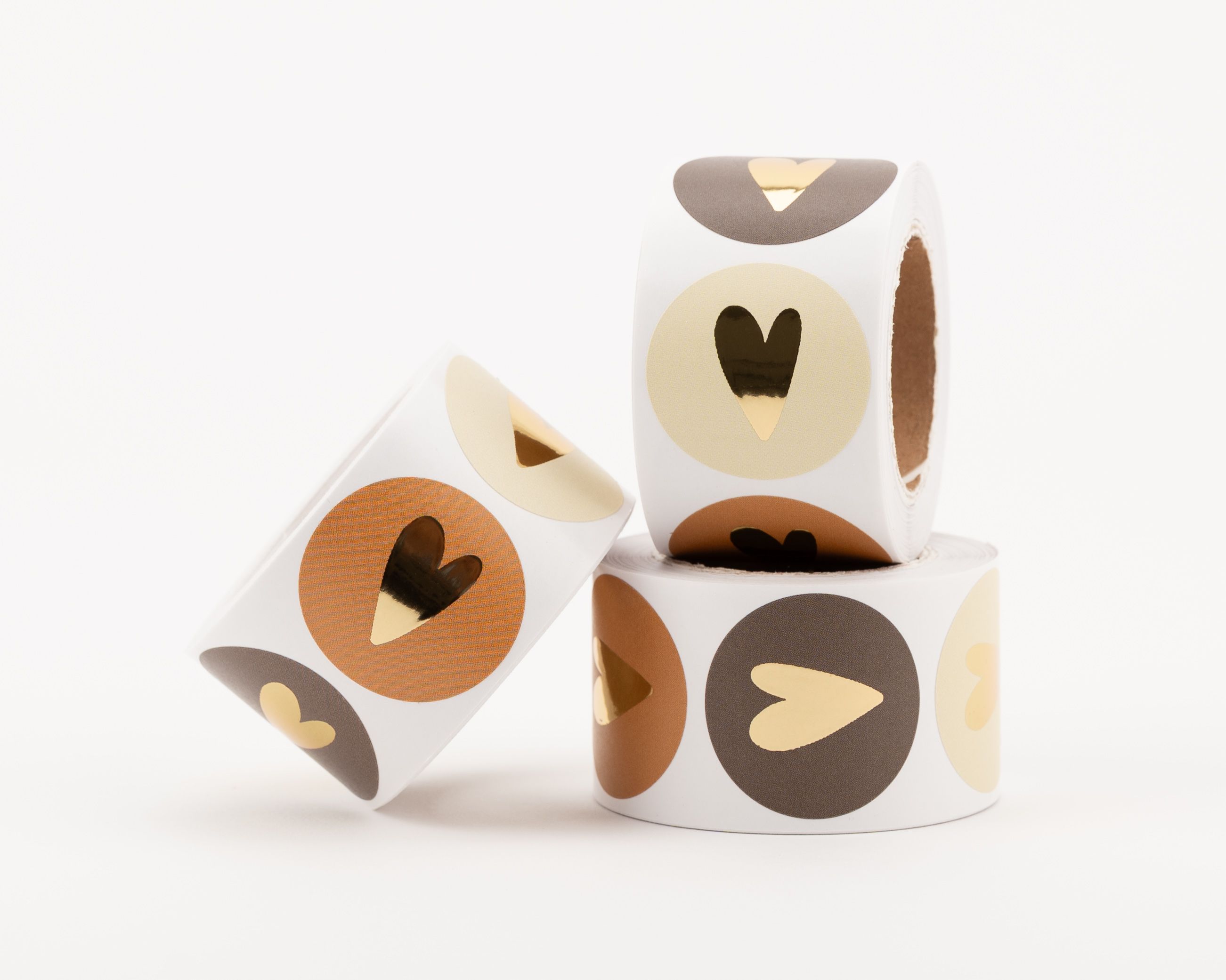 Aufkleber mit verschiedenen Designs, darunter runde Sticker in beige, braun und rostbraun, alle mit glänzendem goldenem Herzmotiv