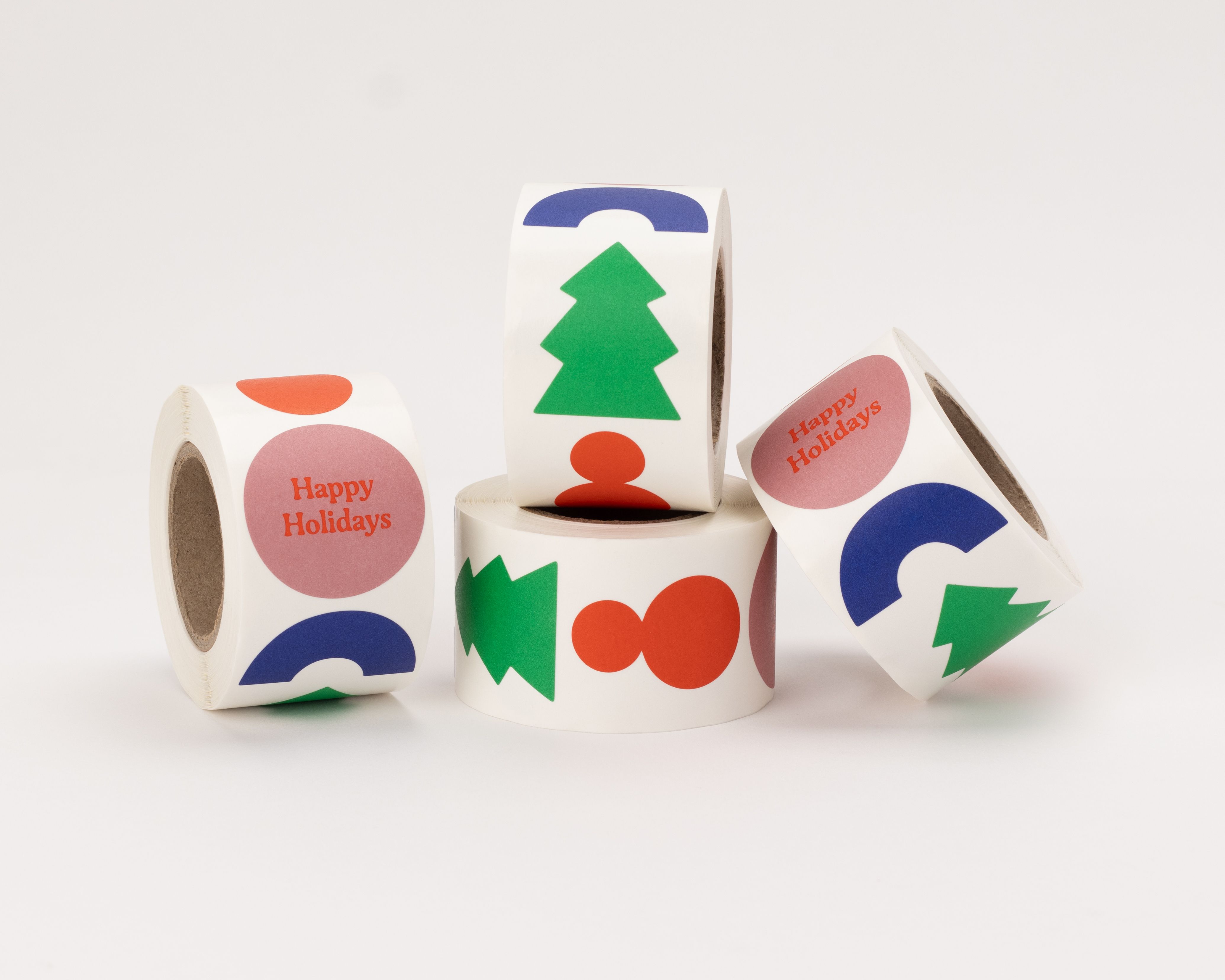 Aufkleber mit vier verschiedenen runden Bauhaus Weihnachtsmotiven. Designs in Rot, Blau und Grün zeigen einen Baum, eine Figur und den Schriftzug Happy Holidays