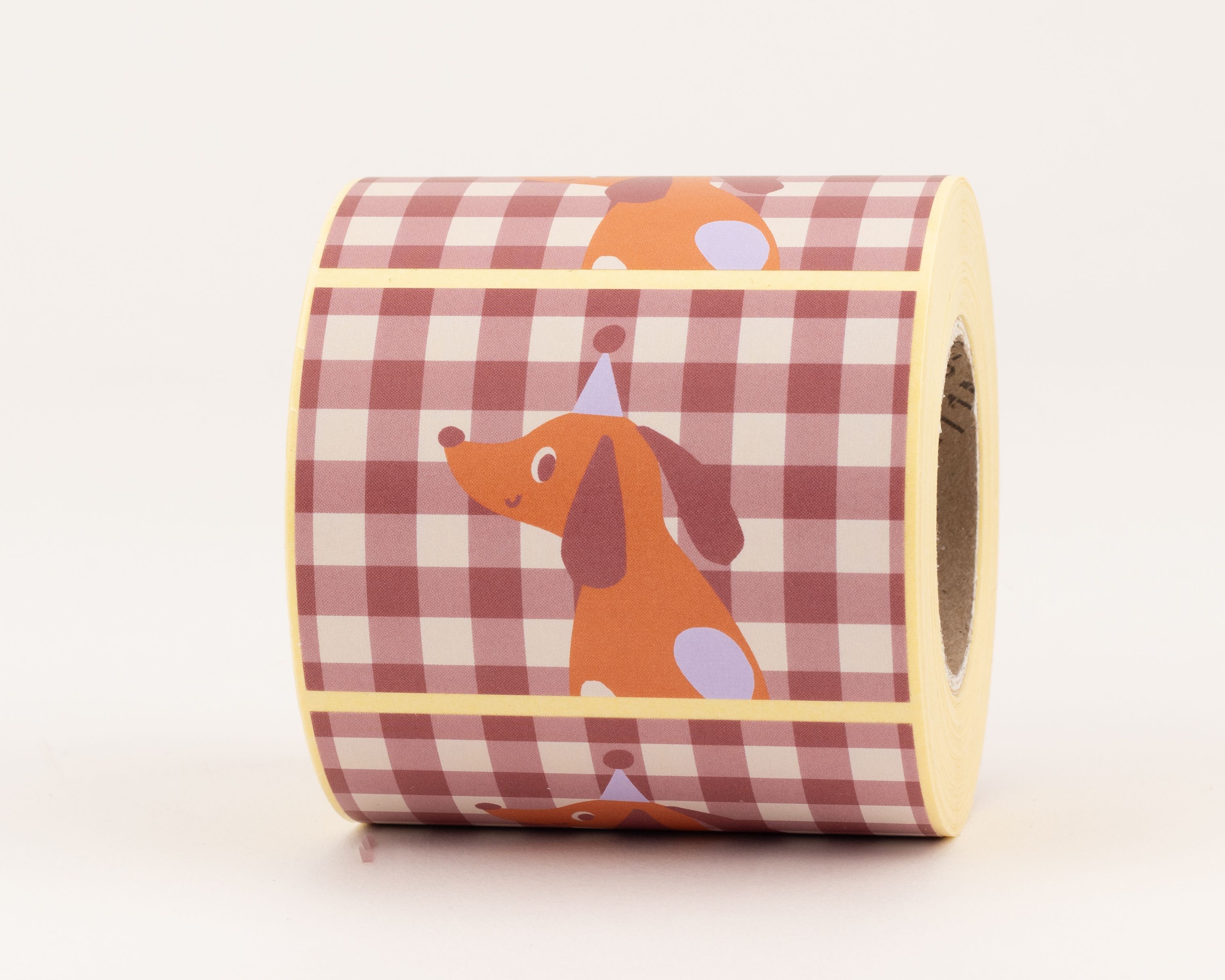 Aufkleber mit orangefarbenen Dackelmotiven, die blaue Partyhüte tragen, auf einem rotbraun-beigen Karomuster