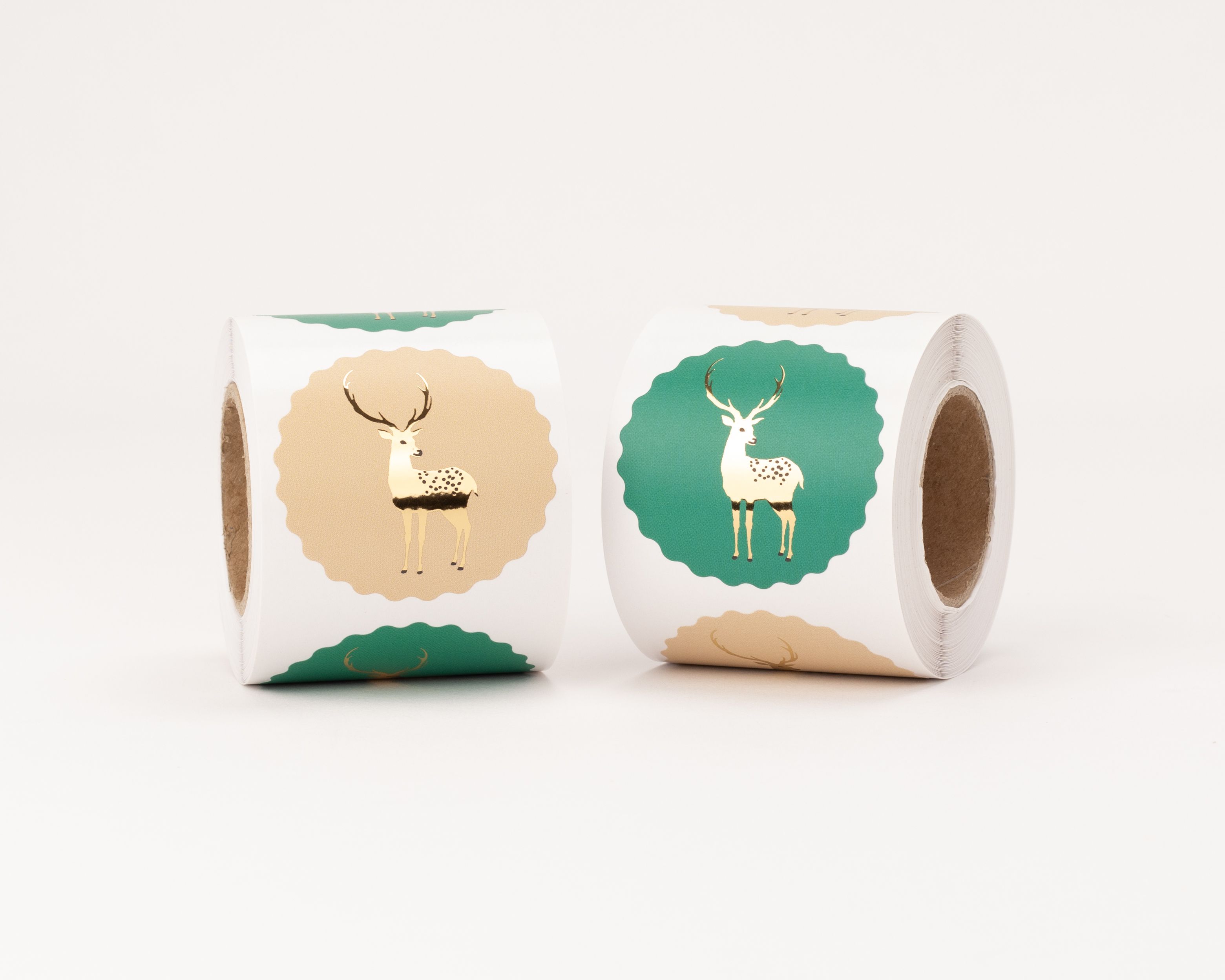 Aufkleber mit zwei verschiedenen Rentier-Motiven in Beige und Grün, jeweils mit elegantem Gold-Effekt und Wellenrand