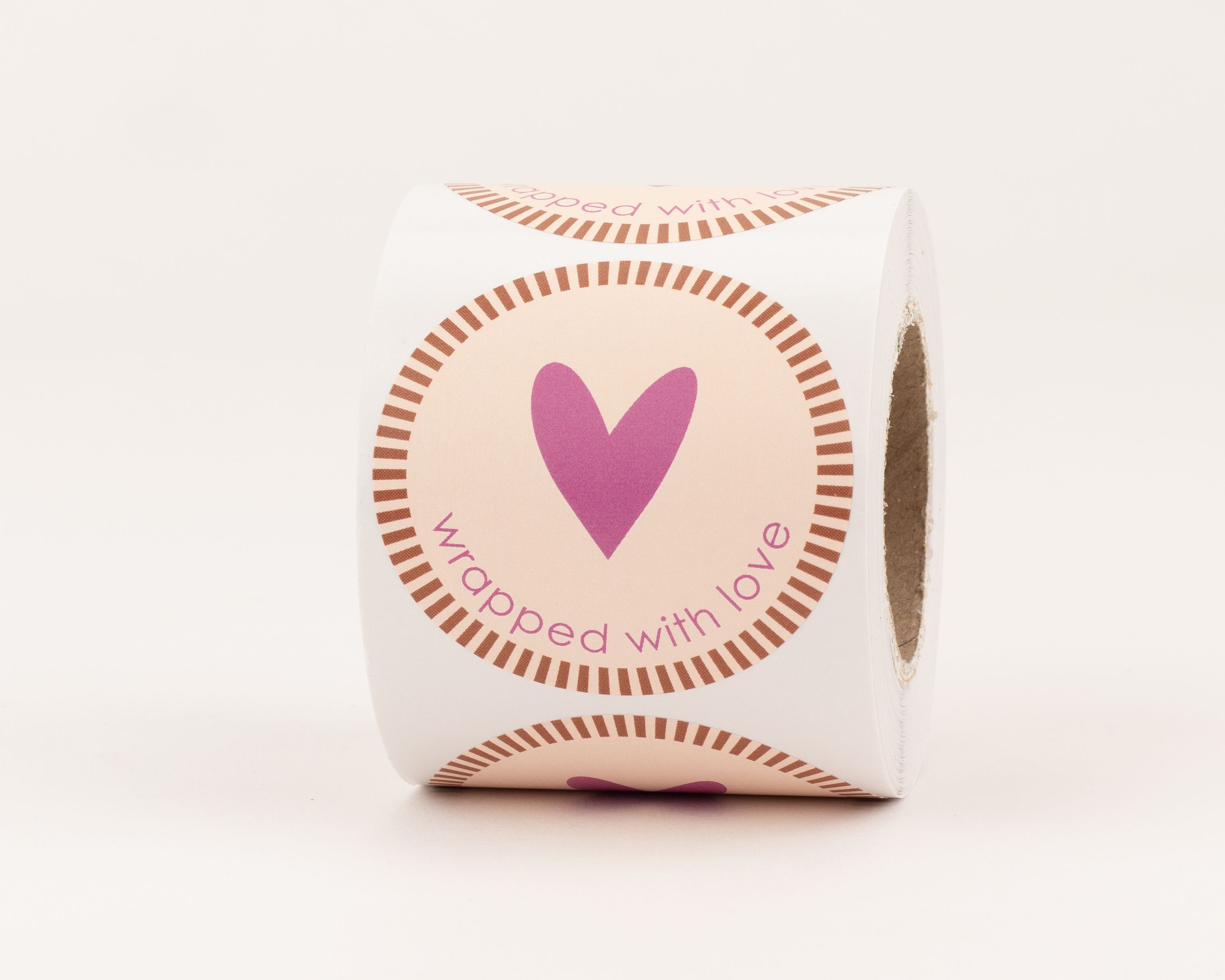 Runde Aufkleber mit magenta Herz auf hellbeigem Hintergrund und braunem Strichrand. Der braune Schriftzug lautet 'wrapped with love'