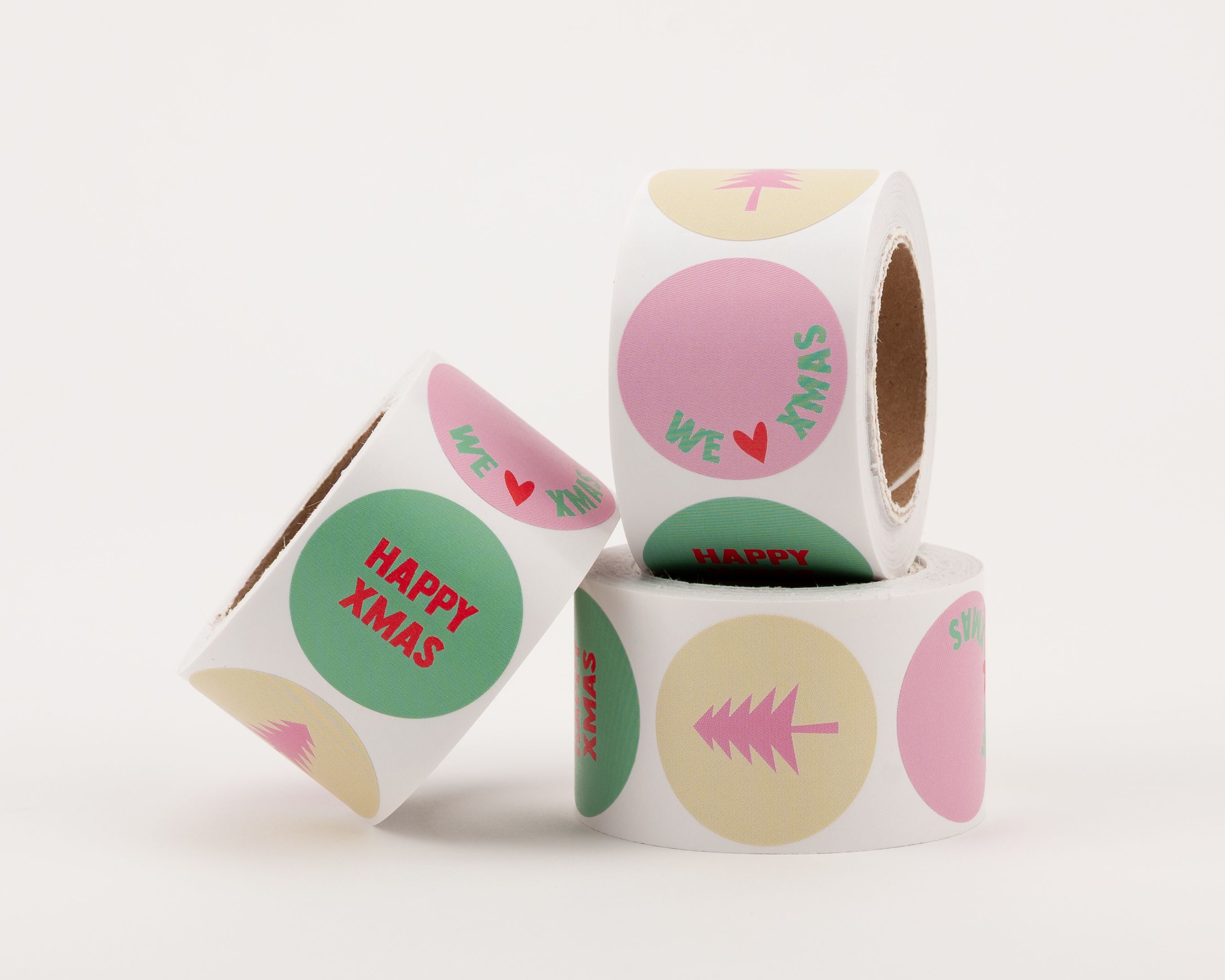 Runde Aufkleber mit verschiedenen Designs in Beige, Pink, Grün. Motive sind 'Happy Xmas', 'We Love Xmas' und ein Weihnachtsbaum
