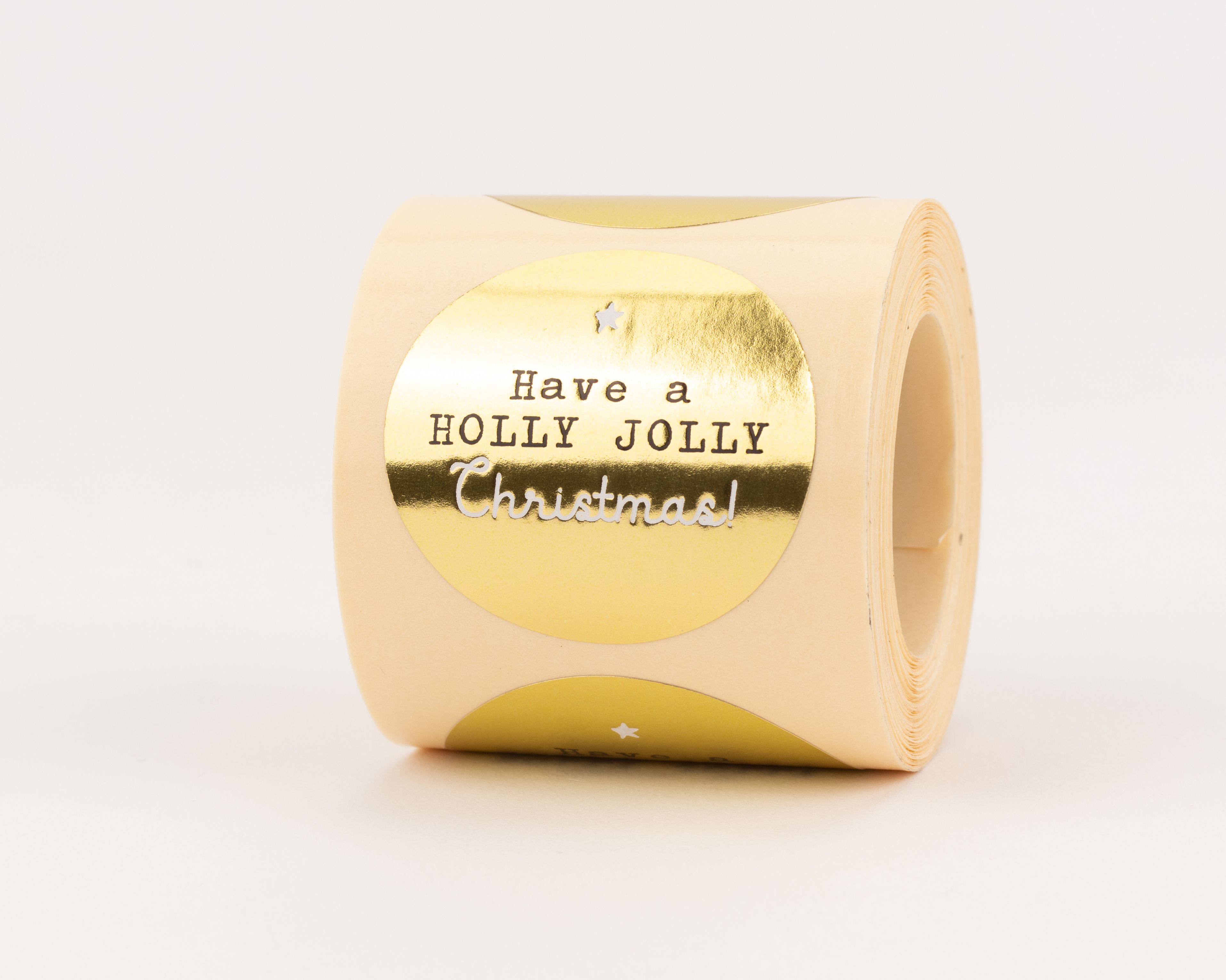 Aufkleber mit rundem Goldmuster, dem Schriftzug 'Have a Holly Jolly Christmas!' in dunkler und silberner Schrift, sowie einem Stern