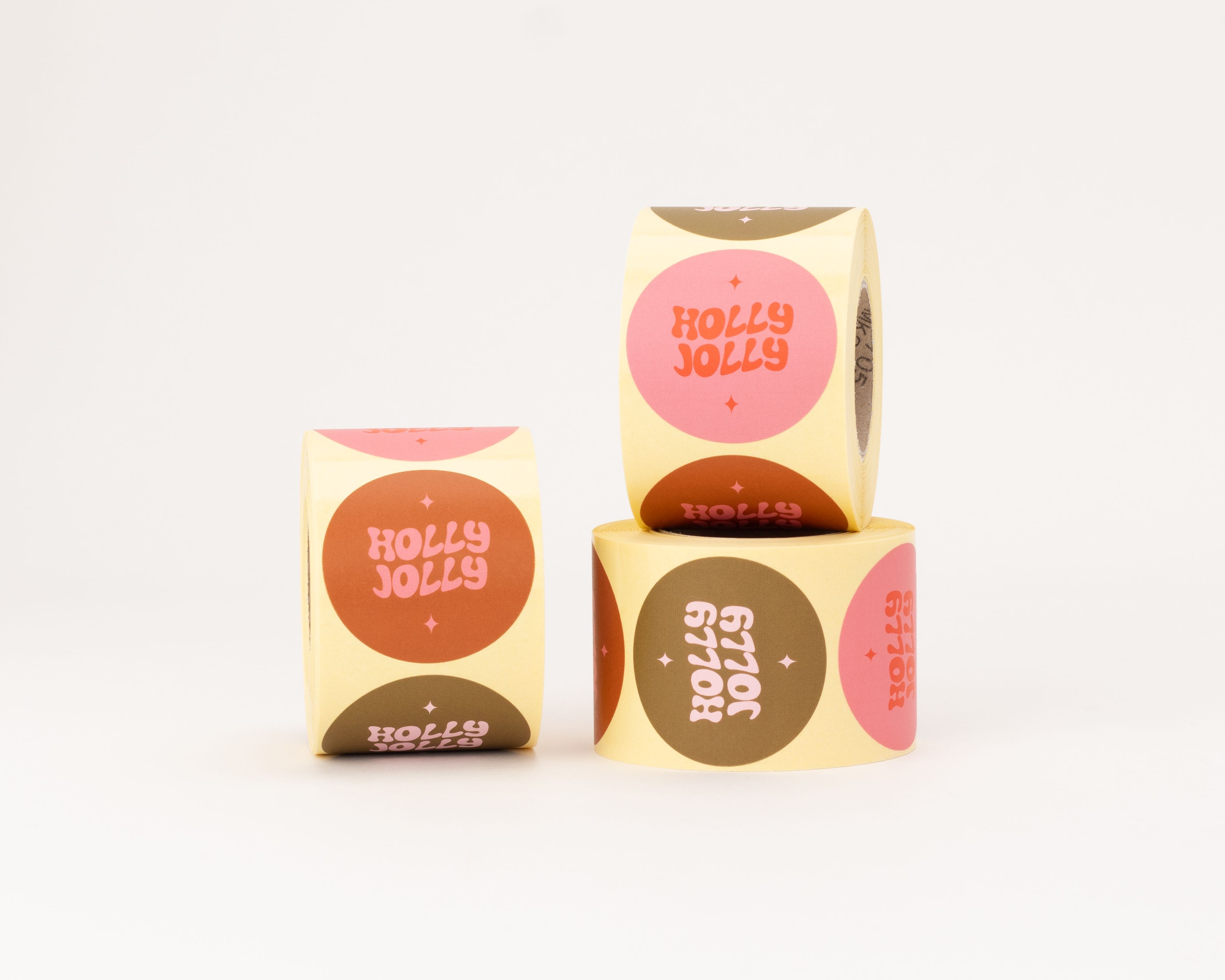 Runde Aufkleber mit verschiedenen Holly Jolly Motiven in Pink, Orange, Rosa und Braun, verziert mit Sternen