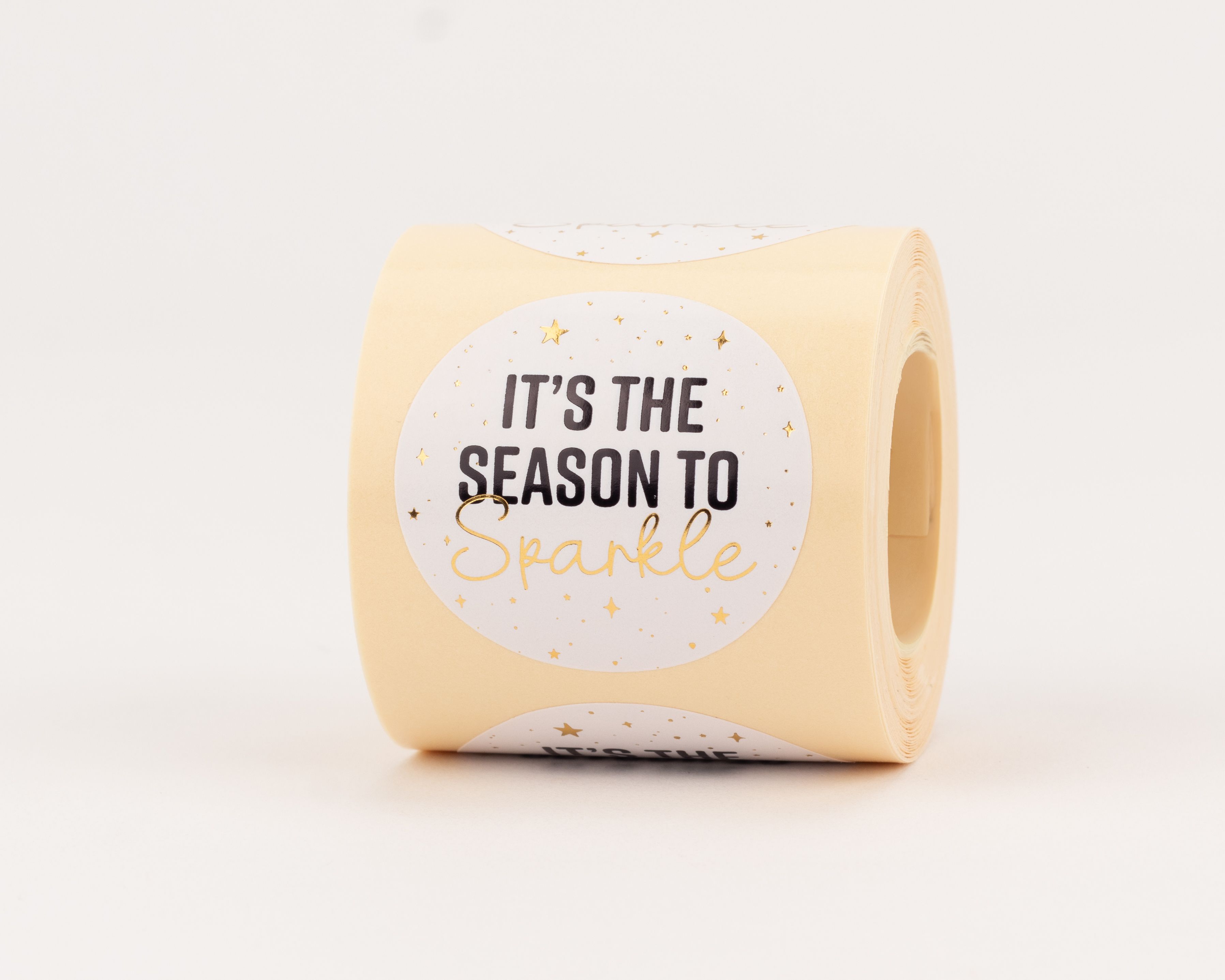 Aufkleber mit weißem Hintergrund, schwarzem Text 'IT'S THE SEASON TO', goldenem Schriftzug 'Sparkle' und kleinen goldenen Sternen