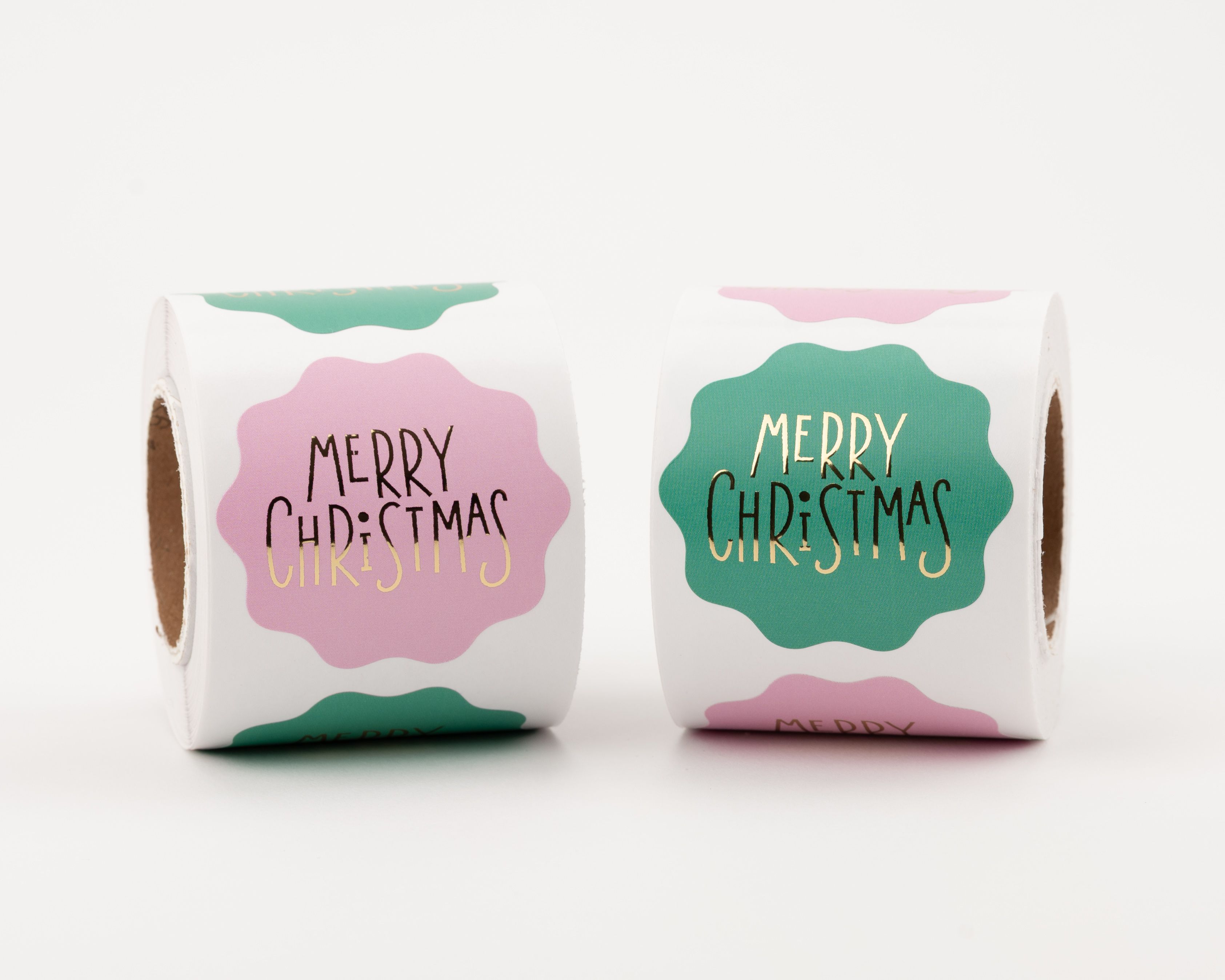 Runde Sticker mit zwei verschiedenen 'Merry Christmas' Designs in Pink und Grün. Die Aufkleber haben goldene und schwarze Schriftzüge