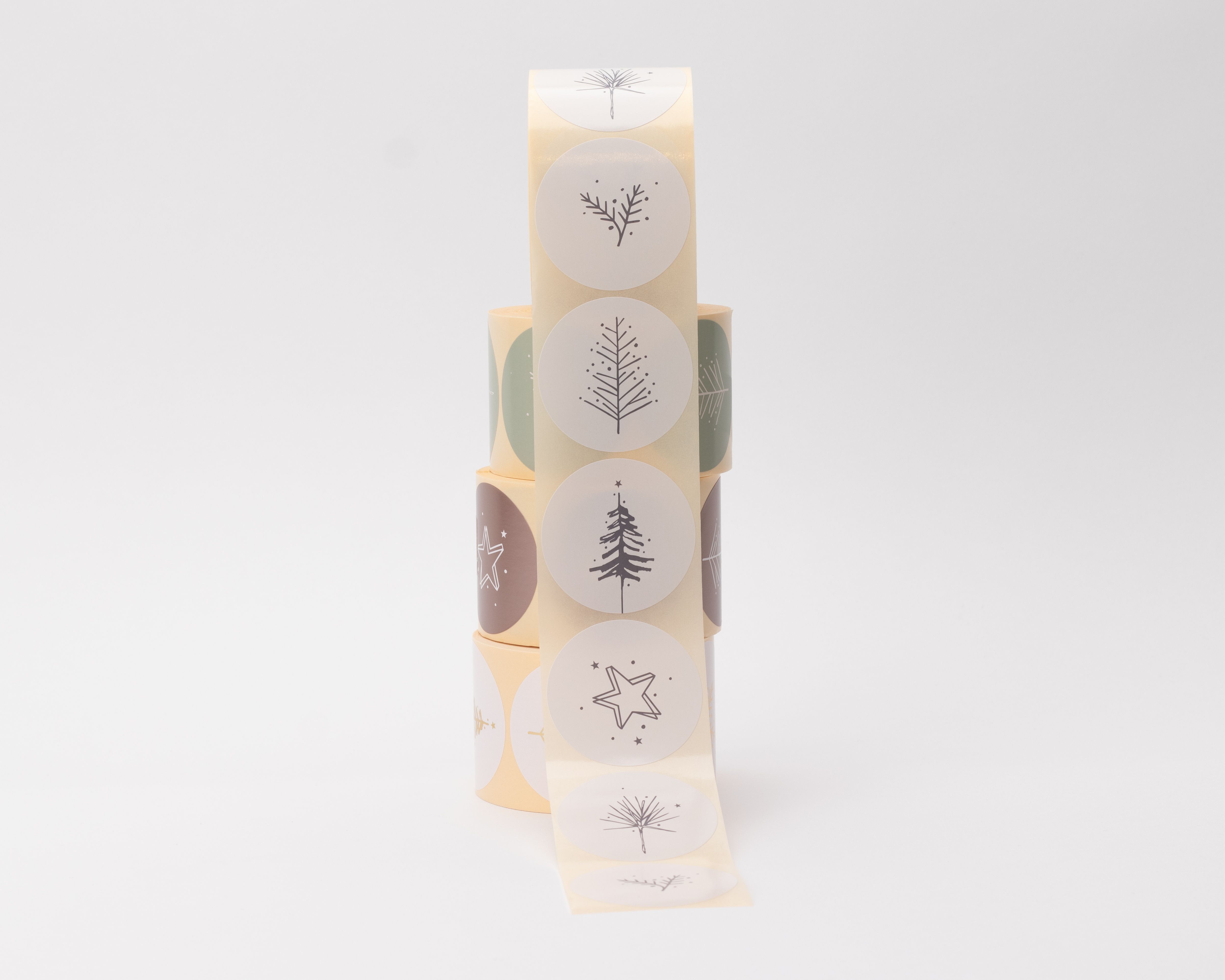 Aufkleber mit fünf verschiedenen Motiven im Skandi-Weihnachts-Stil, wie Tannenbäume, Zweige und Sterne, in dunklem Grau auf runden, hellen Stickern