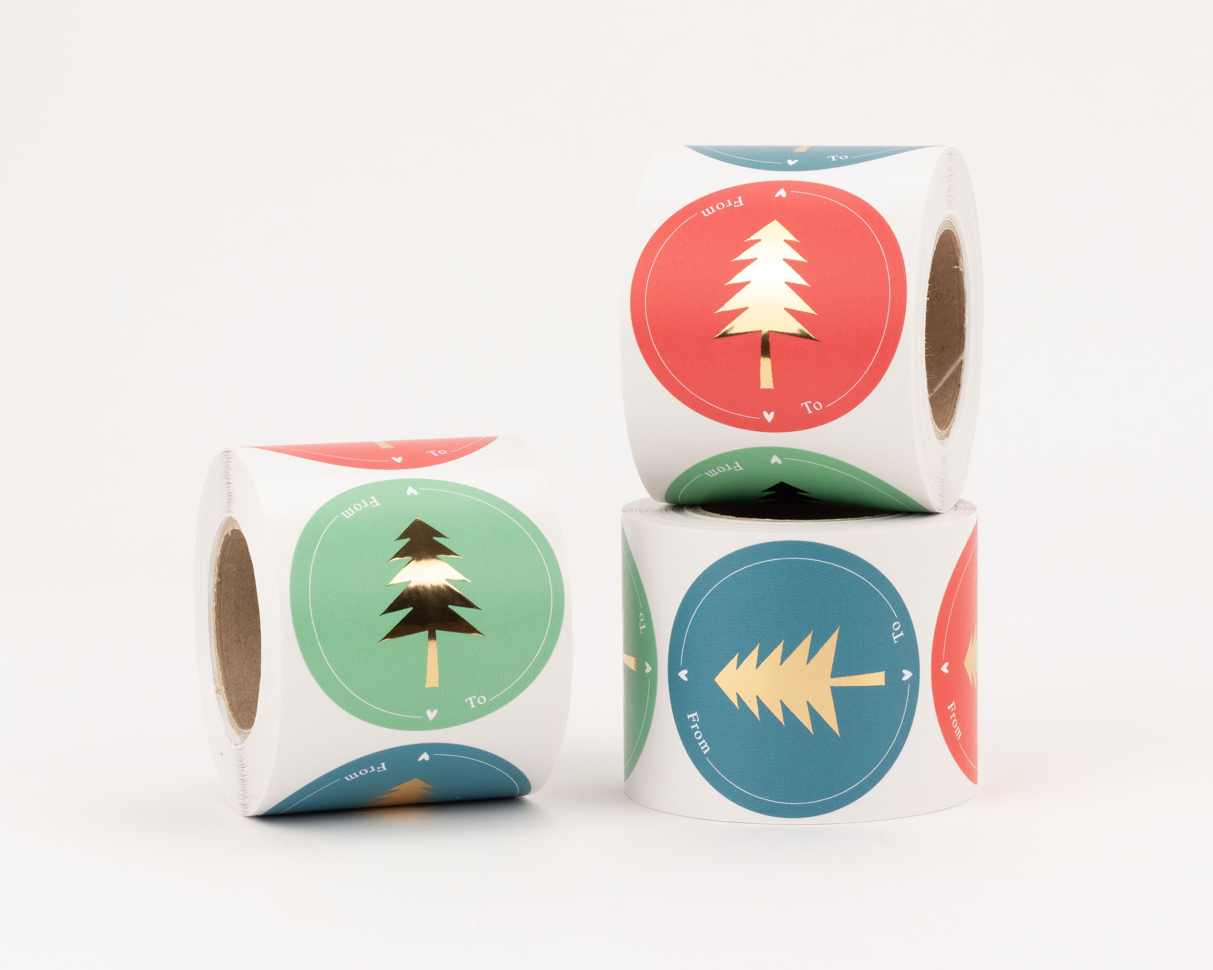 Sticker mit drei verschiedenen runden Tannenbaum-Motiven in Grün, Rot und Petrol. Jeder Aufkleber zeigt einen goldenen Effekt und eine From / To Beschriftung