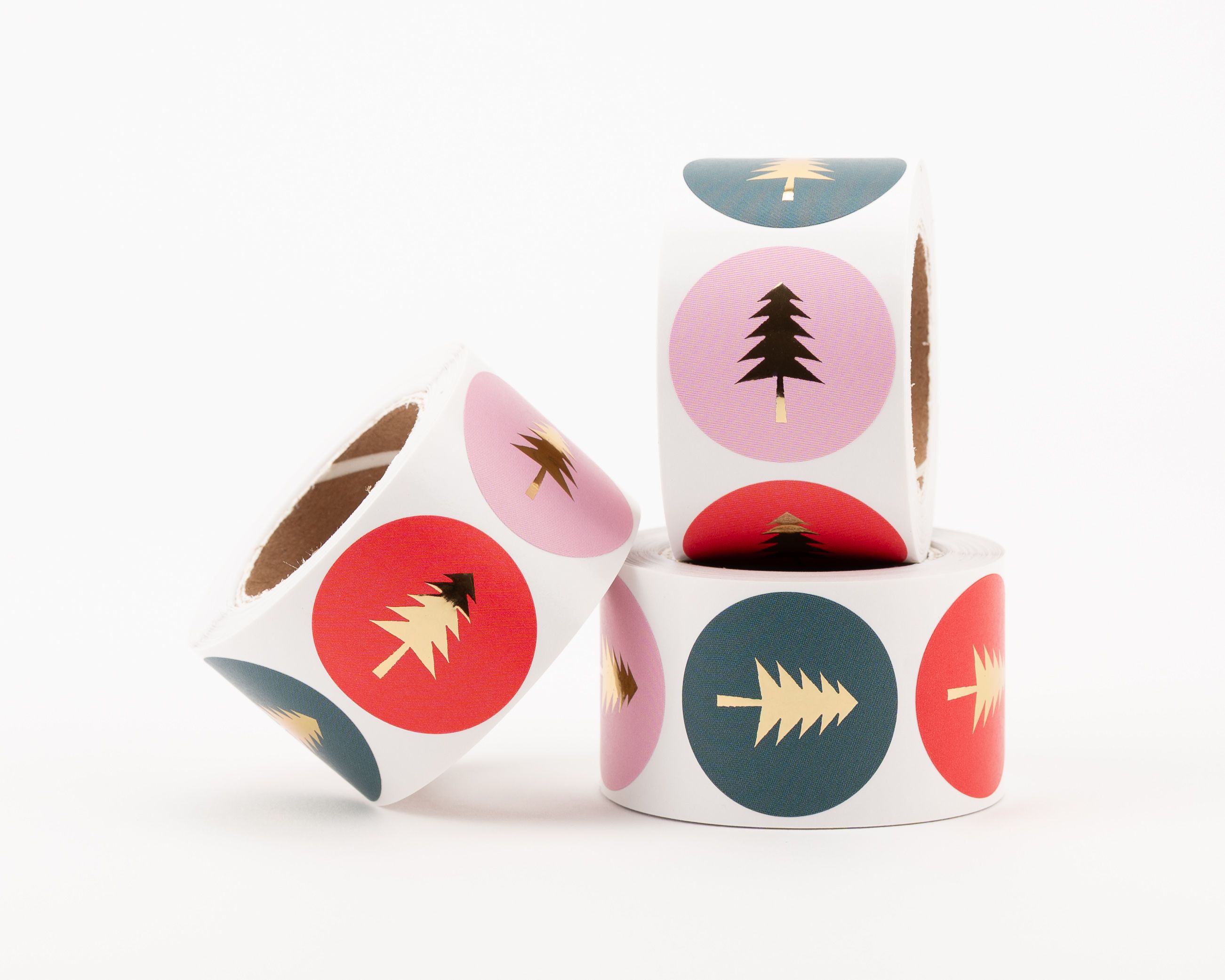 Aufkleber mit drei verschiedenen Tannenbaum-Designs in Rot, Rosa und Petrol, jeweils mit einem glänzenden Gold-Effekt
