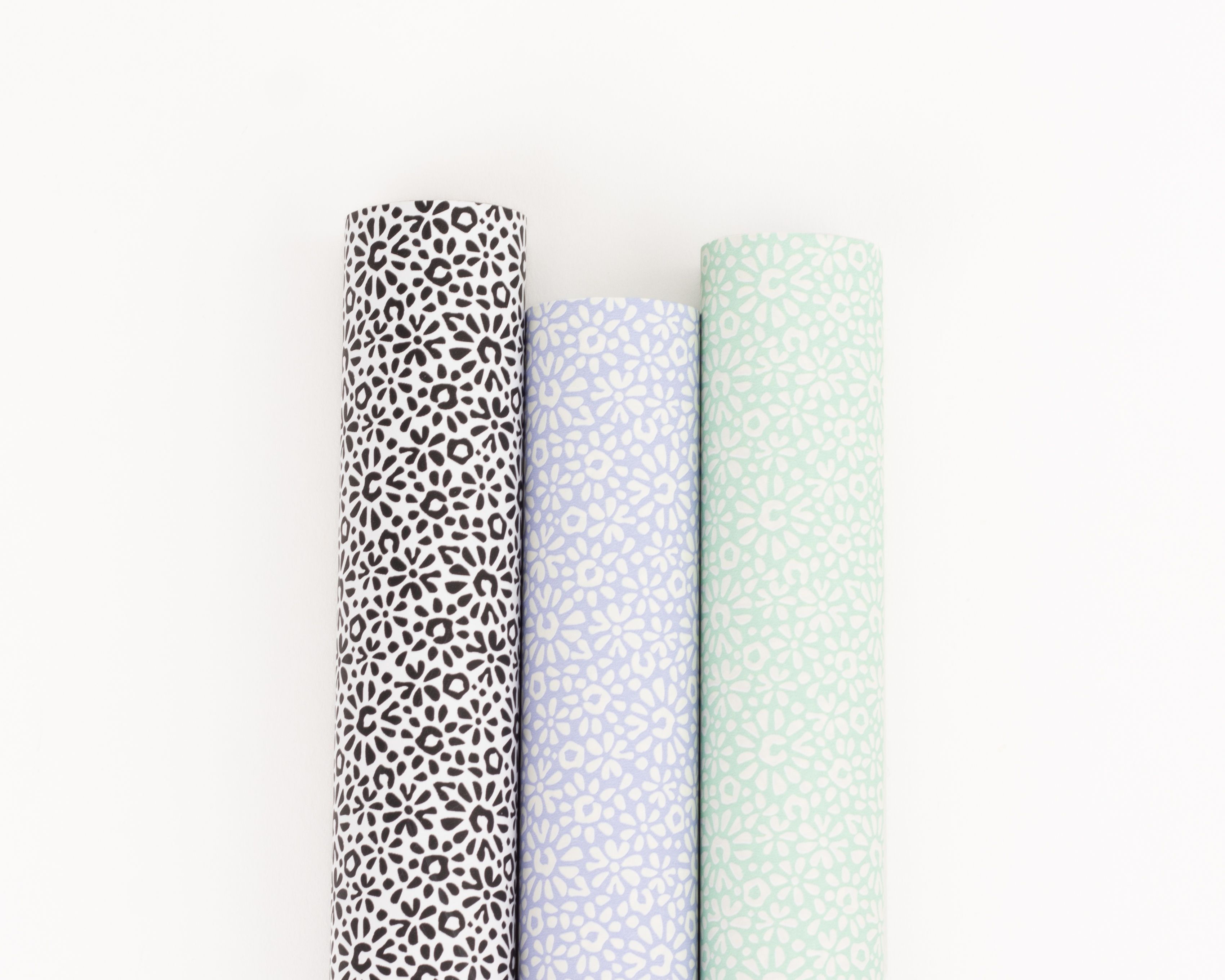 Geschenkpapier-Set mit drei Rollen in Schwarz, Flieder und Minze, nebeneinander arrangiert mit floralen Mustern