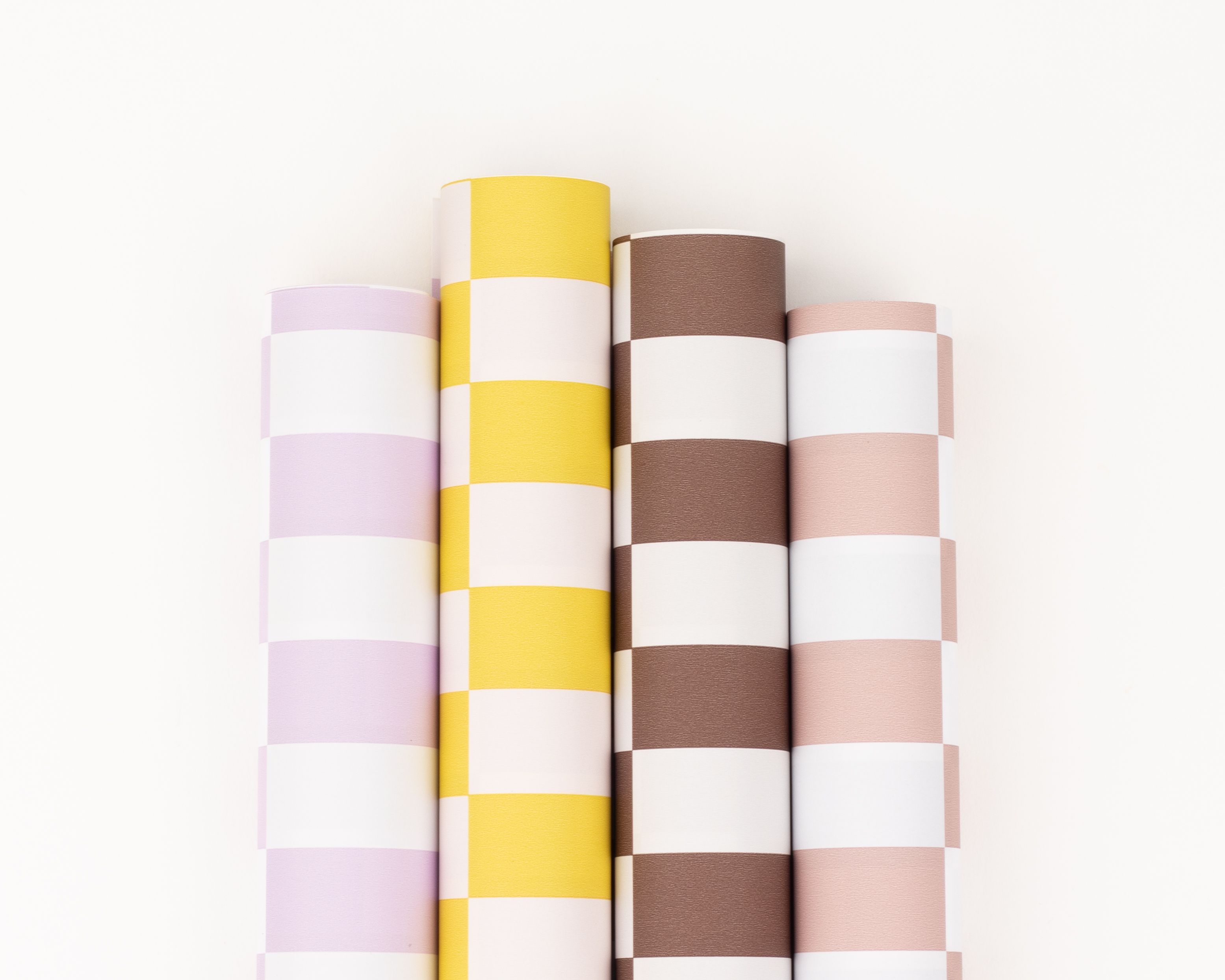 Geschenkpapier-Set mit vier nebeneinander liegenden Rollen und Blockstreifenmuster in Gelb, Hellem Flieder, Braun und Rosa mit Weiß