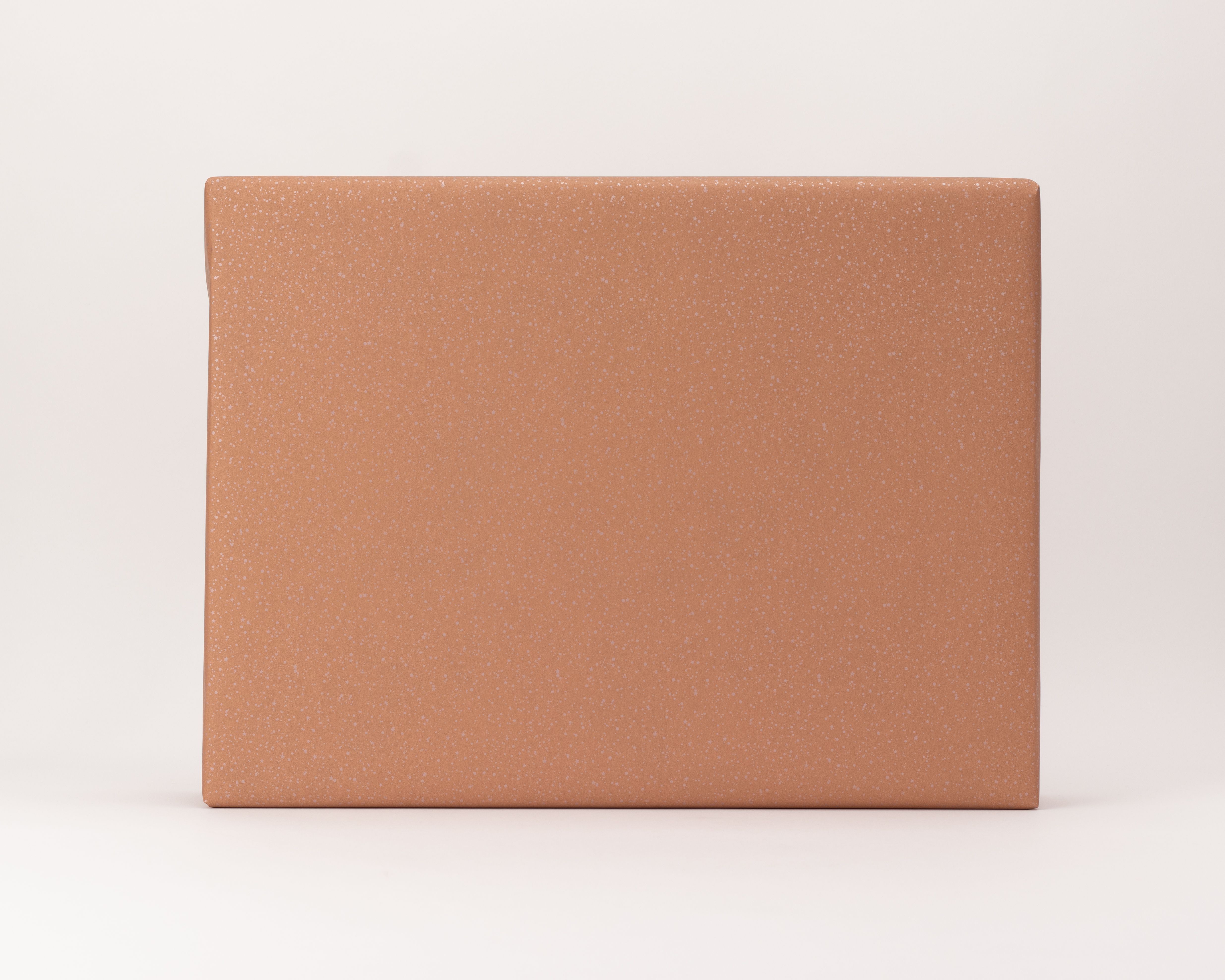 Geschenkpapier-Set: Ein Geschenk liebevoll verpackt in rosa-terrakotta-farbenes Papier mit dezentem Sternenregenmuster