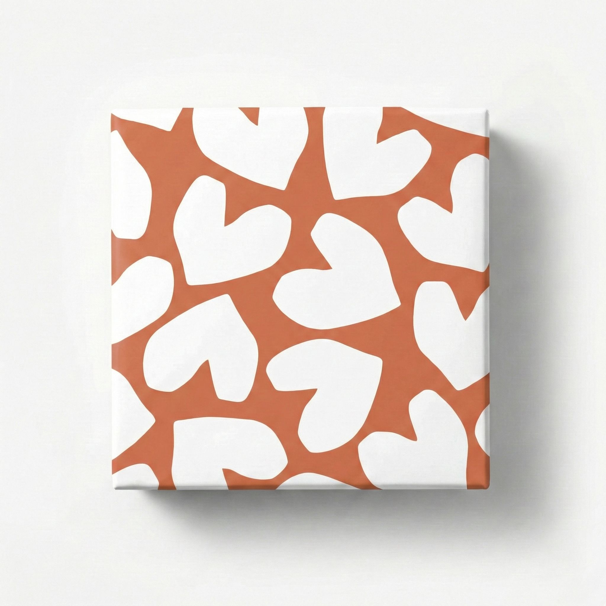 Geschenkpapier mit unregelmäßigen weißen Herzen auf rostbraunem Grund, als verpacktes Geschenk von oben gezeigt