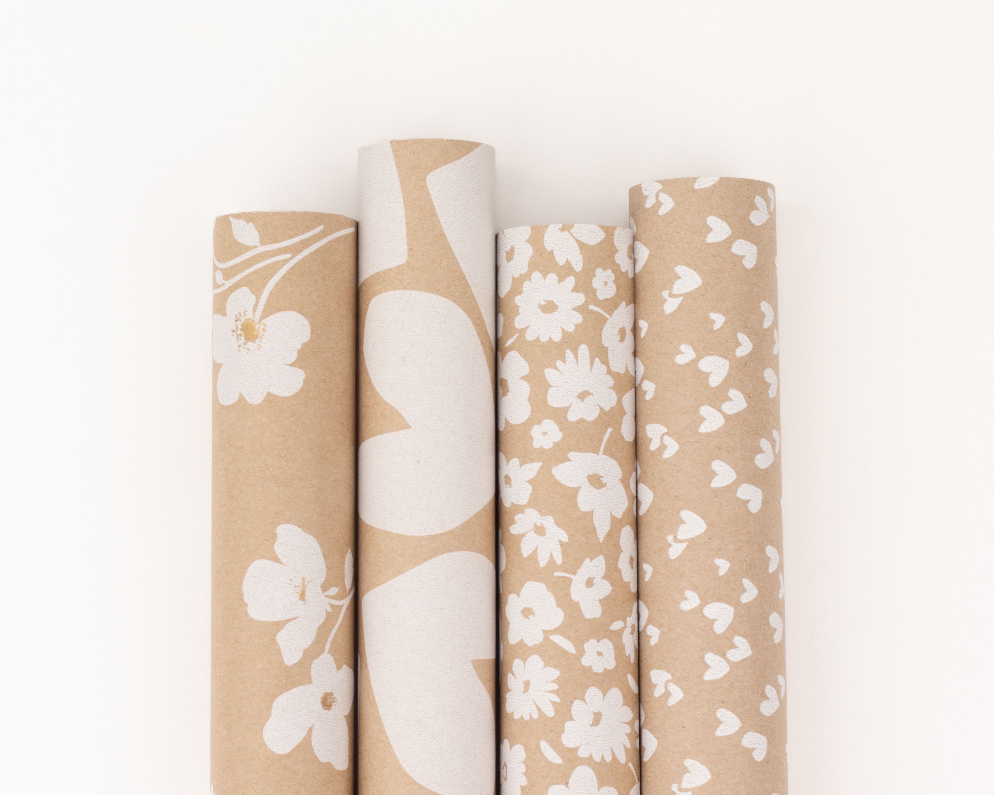 Geschenkpapier-Set mit vier Rollen aus Kraftpapier mit verschiedenen weißen Mustern wie Blumen und Herzen