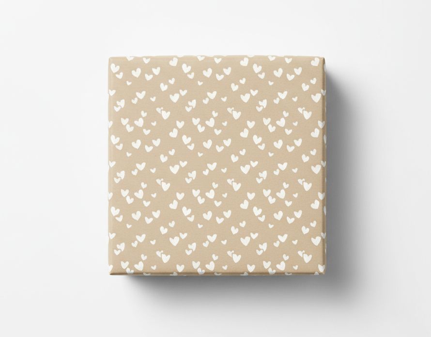 Geschenkpapier mit einem Muster aus vielen kleinen weißen Herzen auf beigefarbenem Kraftpapier, als quadratisches, verpacktes Geschenk von oben gezeigt