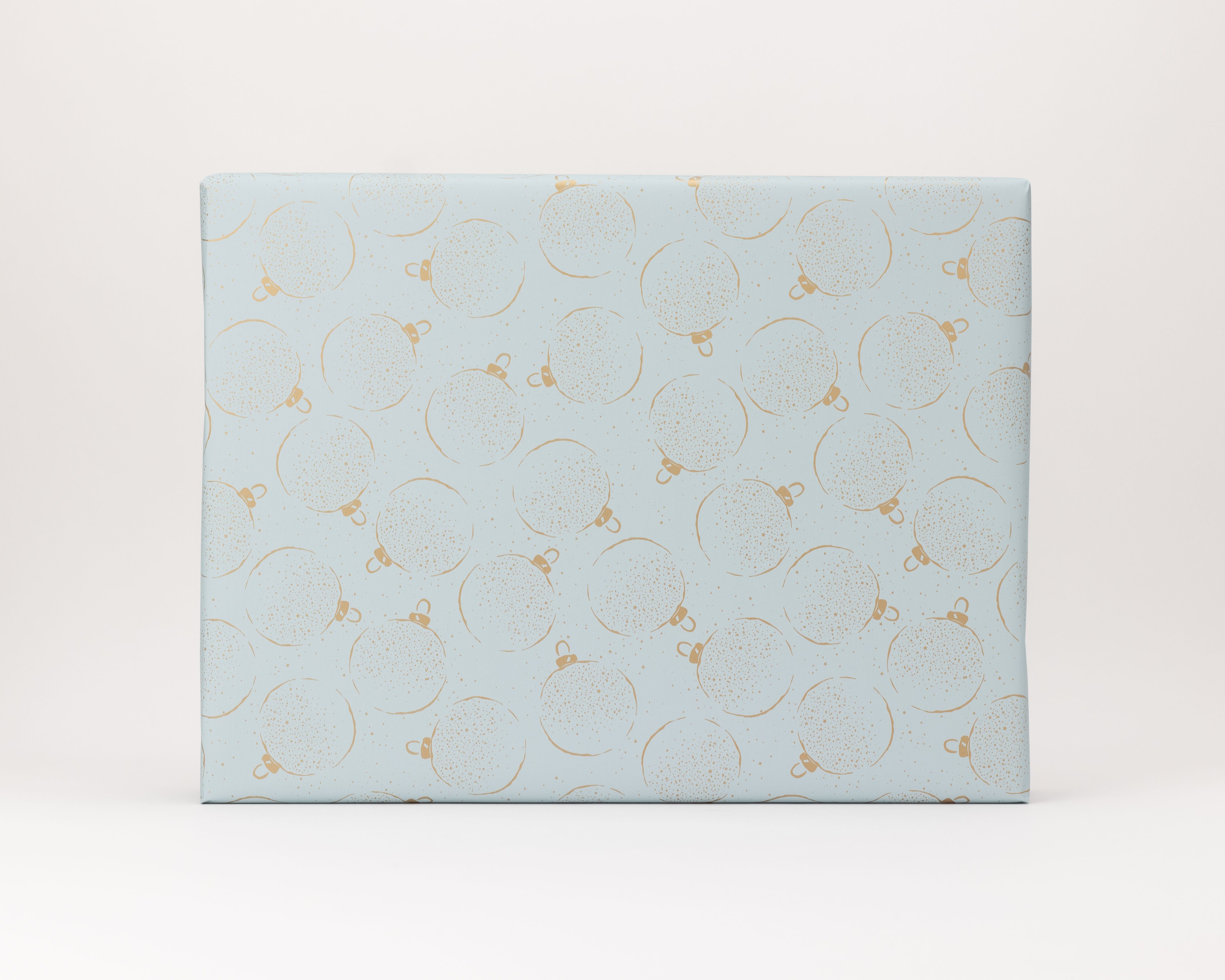 Geschenkpapier-Set zeigt einen festlich verpackten Artikel in eisblauem Papier mit goldenen Weihnachtskugeln und feinen Sprenkeln