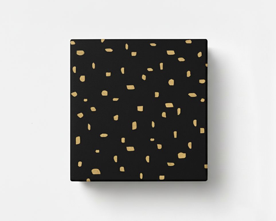 Geschenkpapier mit einem minimalistischen Muster aus unregelmäßigen goldfarbenen Punkten auf schwarzem Grund, dargestellt als verpacktes Geschenk