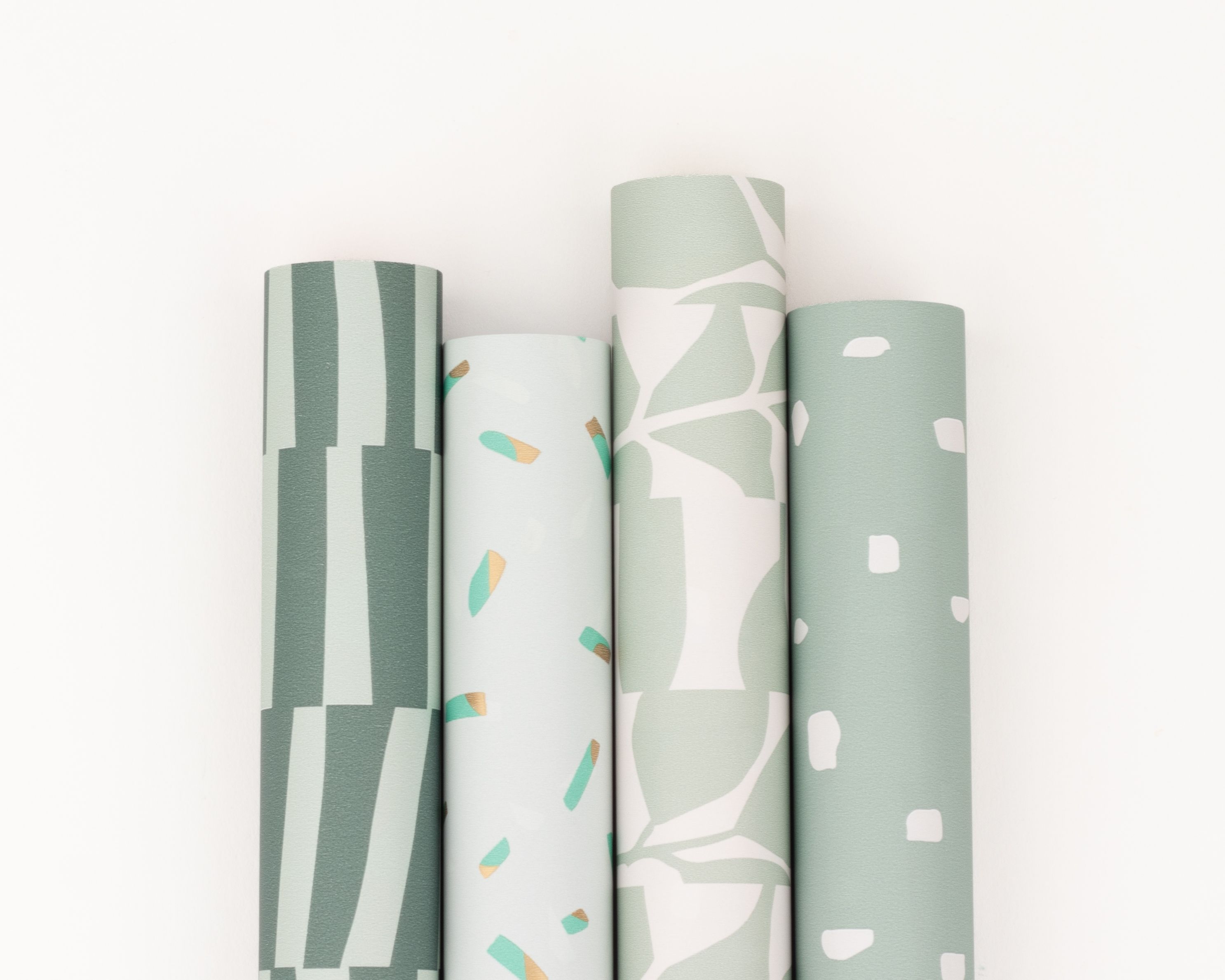 Geschenkpapier-Set mit vier Rollen in Grün-, Blau- und Minttönen, zeigt Muster wie Striche, Sprinkles, Blätter und Punkte
