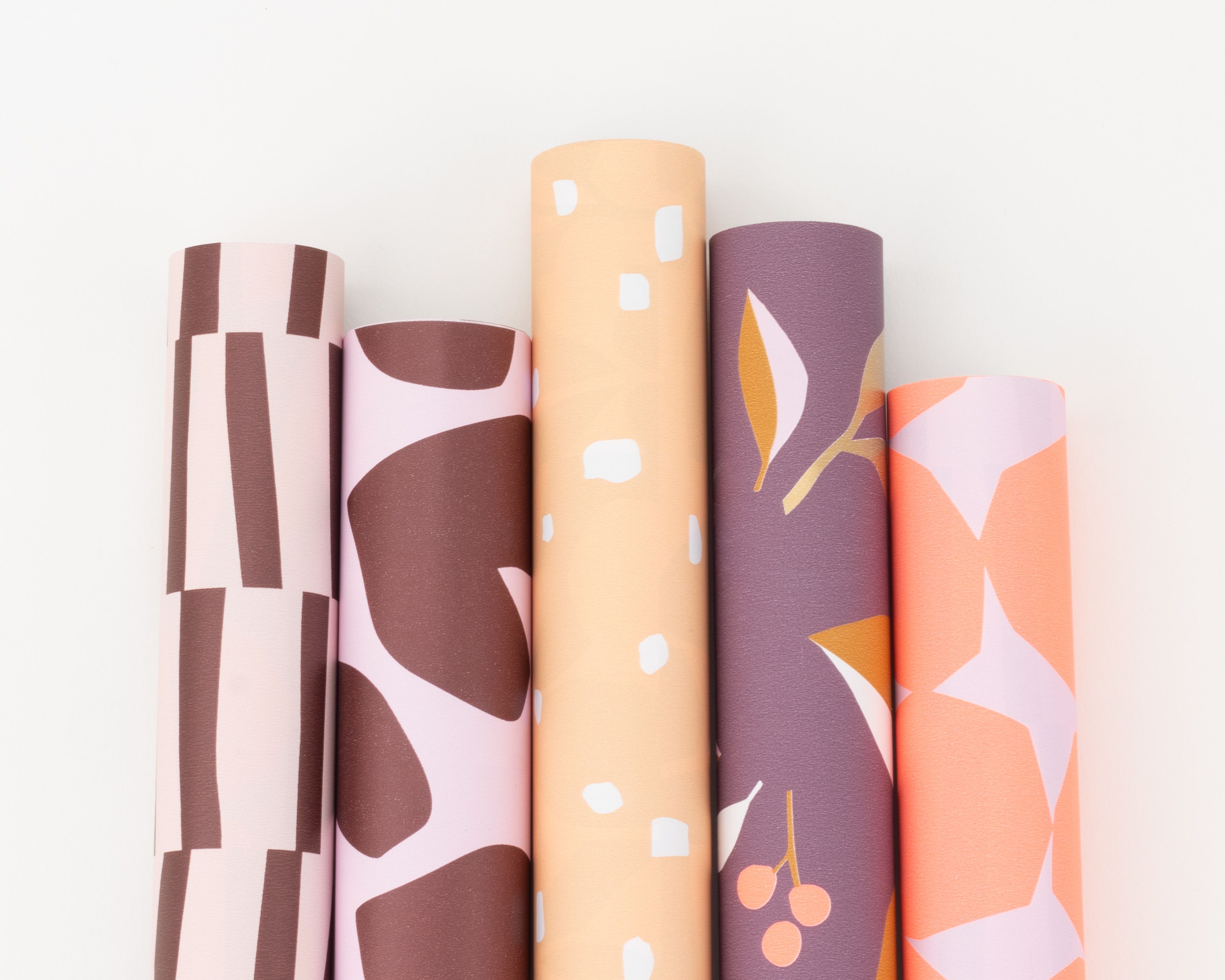 Geschenkpapier-Set mit fünf Rollen in Farbtönen von Weinrot bis Rosa mit verschiedenen Mustern wie Streifen, Punkten und Blättern