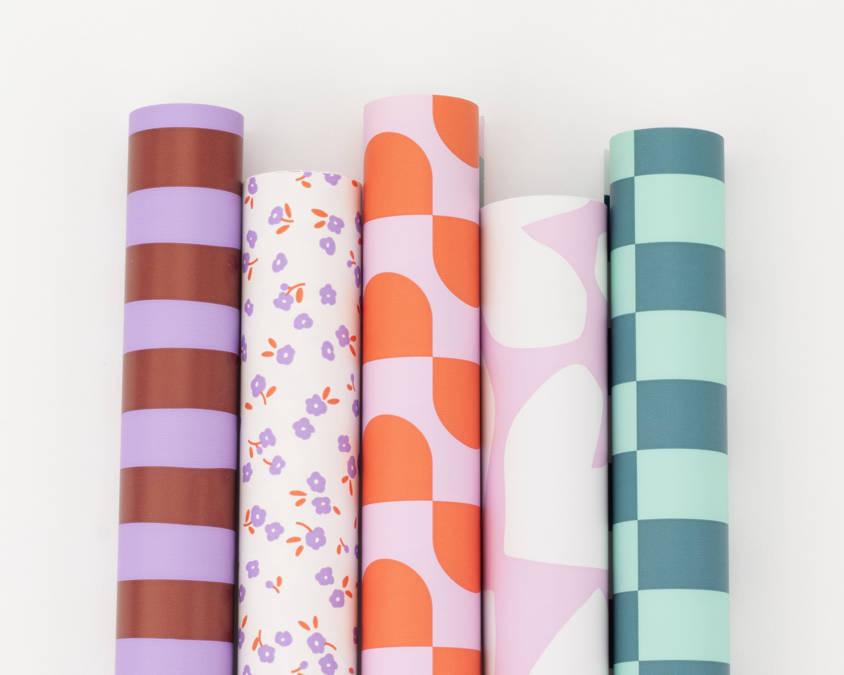 Geschenkpapier-Set mit fünf bunten Rollen mit Streifen, Blumenwiese, Wellenkaros, abstrakten Formen und Schachbrettmuster